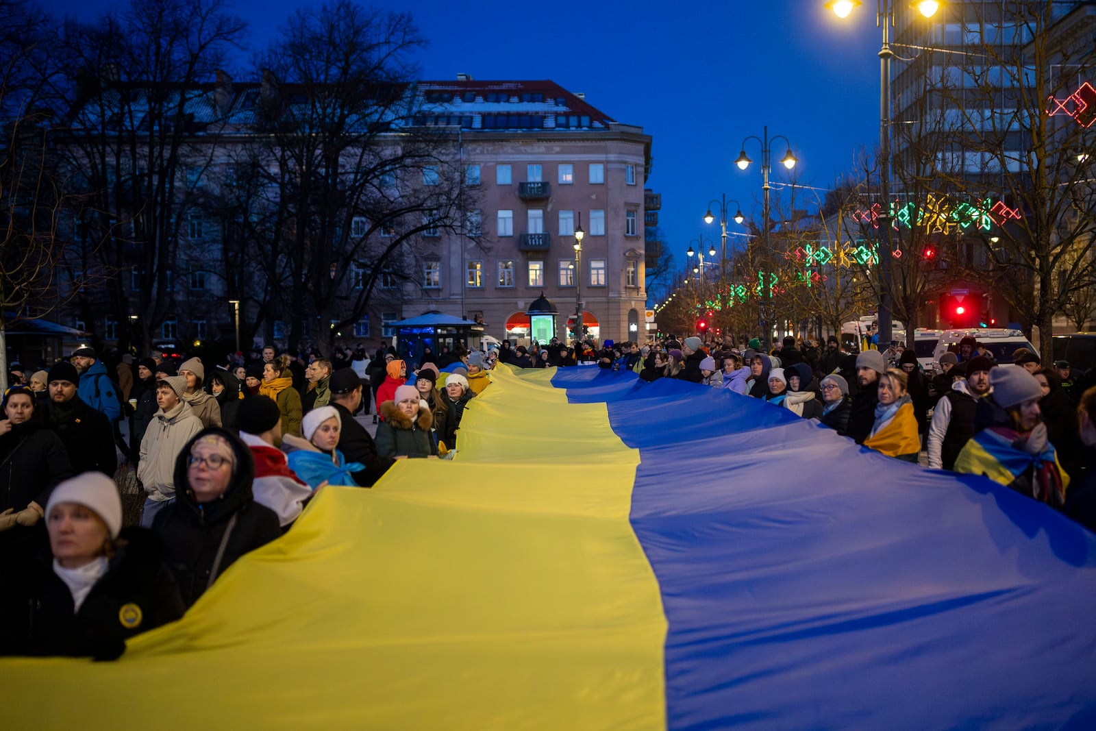 People carry a giant Ukrainian flag to mark the third anniversary of Russia's full-scale invasion of Ukraine, in Vilnius, Lithuania, Sunday, Feb. 23, 2025. (AP Photo/Mindaugas Kulbis)