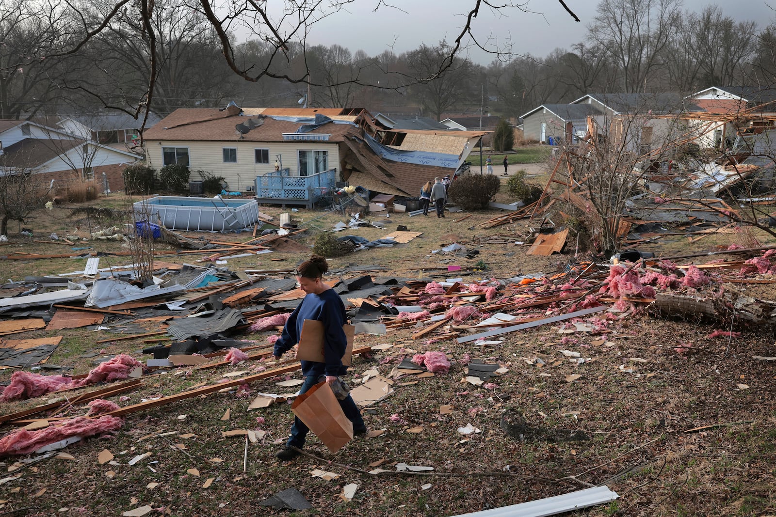 Missy, who declined to give her last name, searches for photographs in a debris field behind a relative's home after a severe storm in Bridgeton, Mo., Saturday, March 15, 2025. (Robert Cohen/St. Louis Post-Dispatch via AP)