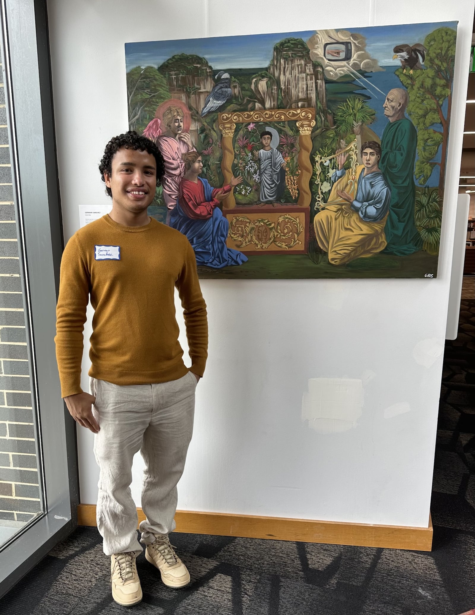 German Sanchez (Colombia) is seen with his painting, “Con Dolor Comeras de ella Todos los Dias de tu Vida," at the downtown Dayton Metro Library. CONTRIBUTED