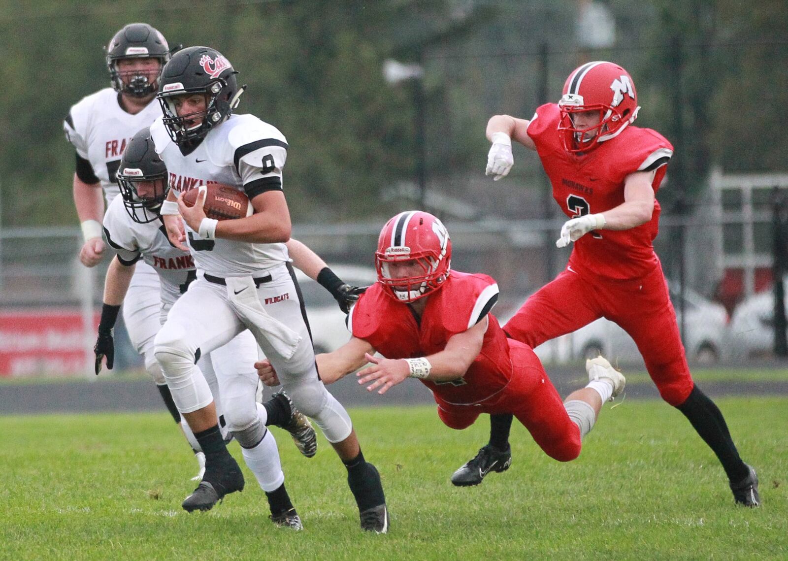 Franklin QB Braden Woods (with ball) eludes Devin Oligee (4) and Connor Blaylock of Madison. Franklin defeated host Madison 42-6 in a Week 1 high school football opener on Friday, Aug. 30, 2019. MARC PENDLETON / STAFF