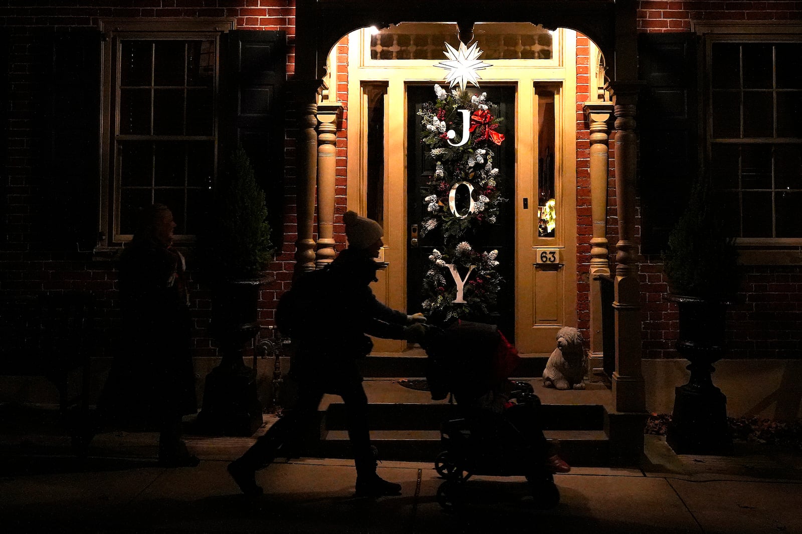 A woman pushes a stroller in front of a house decorated with a Moravian star and Christmas wreaths in Bethlehem, Pa., on Sunday, Dec. 1, 2024. (AP Photo/Luis Andres Henao)