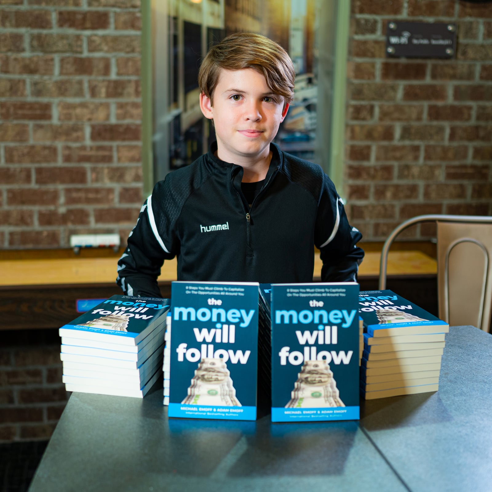 Adam Emoff, 14, is an eighth-grader in Oakwood. He is already the author of more than 23 books. He is shown with his latest, The Money will Follow, a collaboration with his father, Mike. CONTRIBUTED