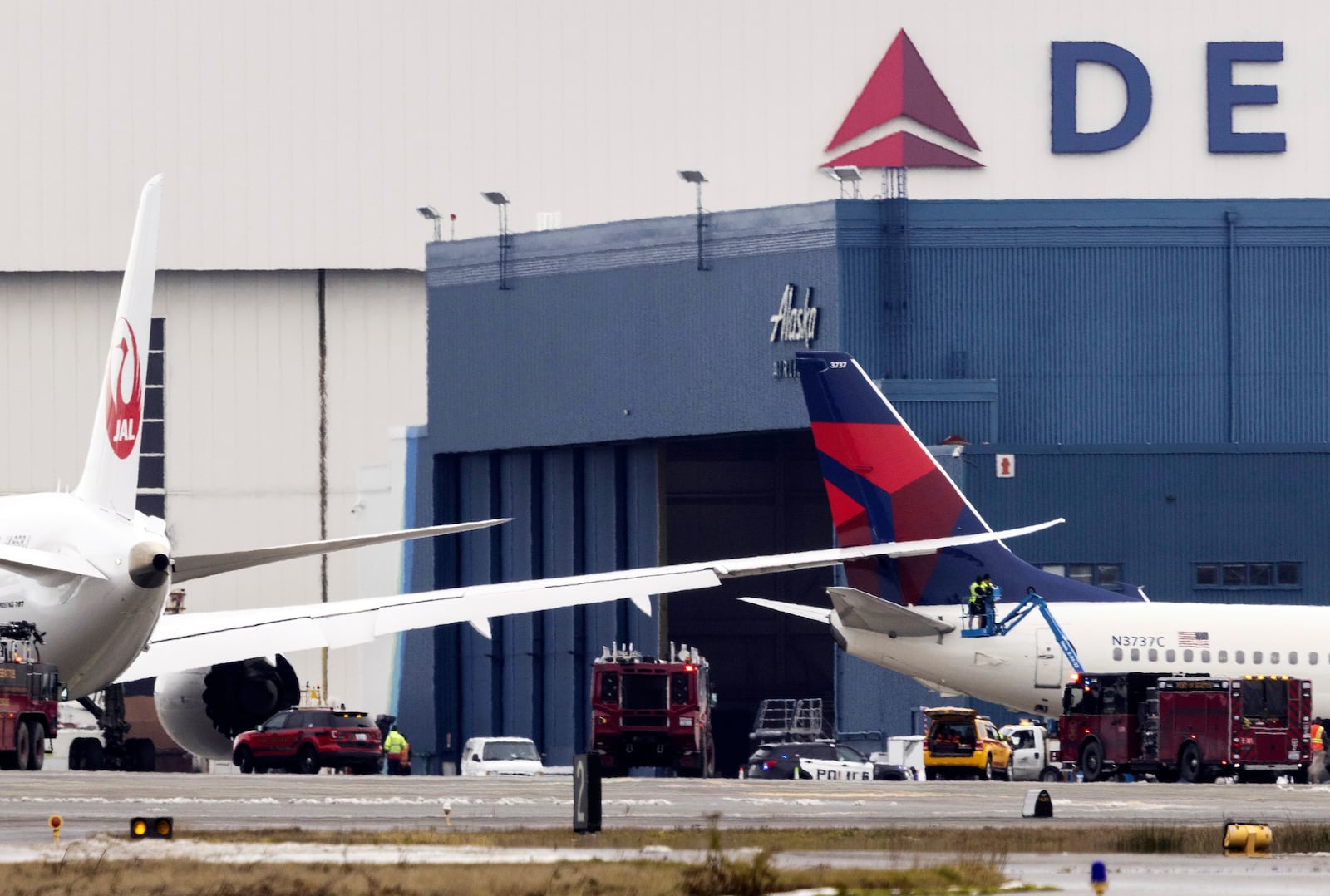 Workers on a lift check the area where the wing of a Japan Airlines jet went into the tail of a Delta Air Lines jet at the south end of a runway at Seattle-Tacoma International Airport on Wednesday, Feb. 5, 2025. (Ellen M. Banner/The Seattle Times via AP)