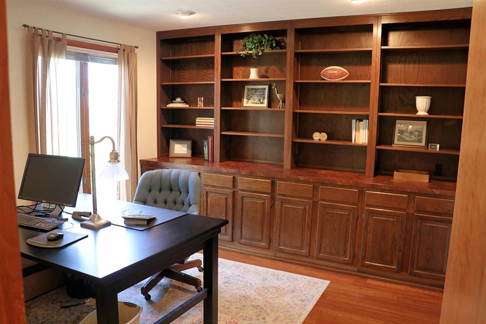 A study has a wall of built-in bookcases and cabinetry.