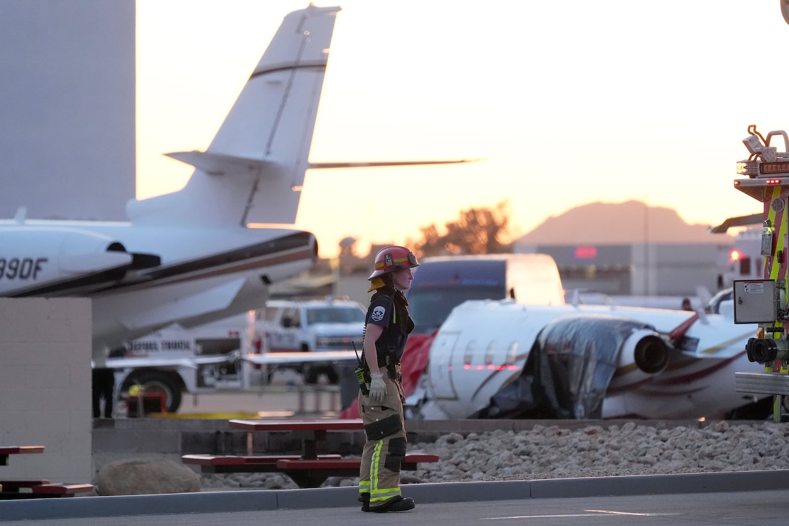 A member of the Scottsdale Fire Department stands near a crashed Learjet at Scottsdale Airport after it collided with a parked plane Monday, Feb. 10, 2025, in Scottsdale, Ariz. (AP Photo/Ross D. Franklin)