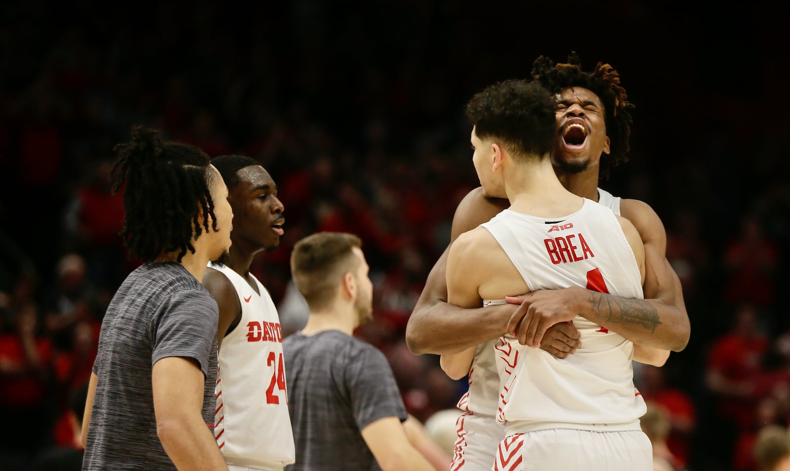 Dayton's Koby Brea gets a hug from DaRon Holmes II after making a go-ahead 3-pointer in the final minute against Davidson on Saturday, March 5, 2022, at UD Arena. David Jablonski/Staff