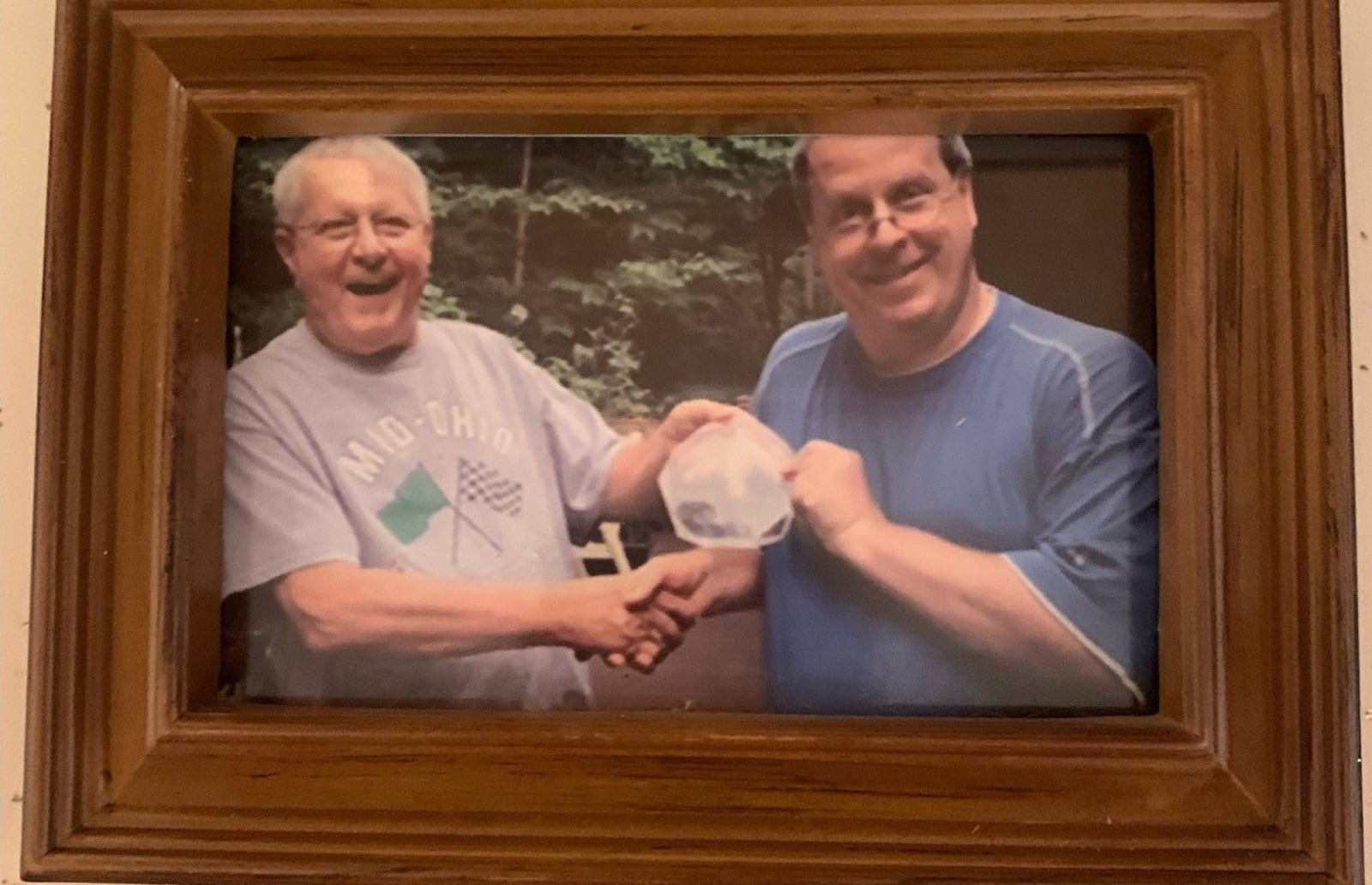 Father and son sportsmen Ed Gyenes (left) and son Greg hold the family’s March Madness trophy. Ed was an All-City baseball player at Fairmont High, got a scholarship to Ohio State, by his mid-20s he was a basketball referee in the Big Ten, Mid-American Conference and the Ohio Valley Conference and refereed the 1971 NCAA Tournament Far West Regional. Sunday he will  b attending his 72nd Indy 500, accompanied by his son Greg, a Hall of Fame basketball player at Miamisburg High, who played college ball at Muskingum and later coached at Miamisburg High. A longtime teacher at Miamisburg High, Greg estimated he will be attending his 35th Indy 500 on Sunday (Contributed Photo)