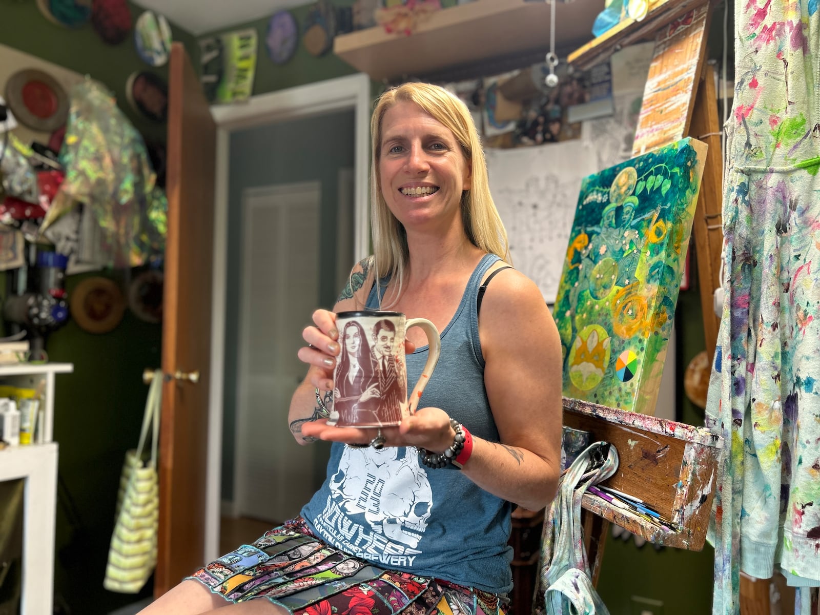 Artist Amy Kollar Anderson relaxes in her studio, wearing one of her handmade skirts and holding tea in a mug made by Elizabeth Dearth of Artifact Pottery.