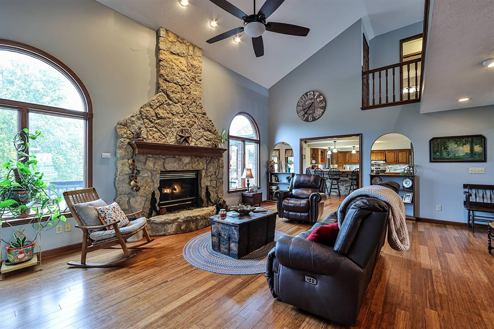 The great room with a vaulted ceiling. Arched windows flank the stone, gas fireplace with wood-beam mantel and curved stone hearth. The same arched design is in the cutouts that flank the entry from the great room into the kitchen. CONTRIBUTED PHOTO