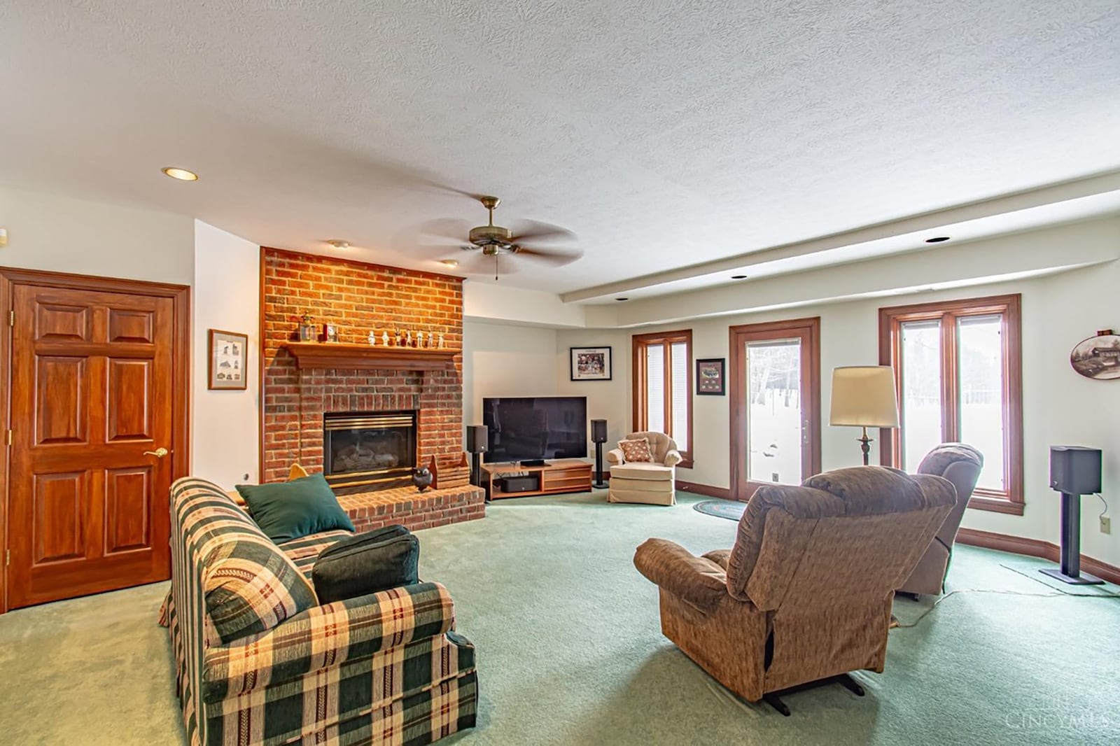 The lower level family room has carpeting, a ceiling fan and a door walking out to a patio.