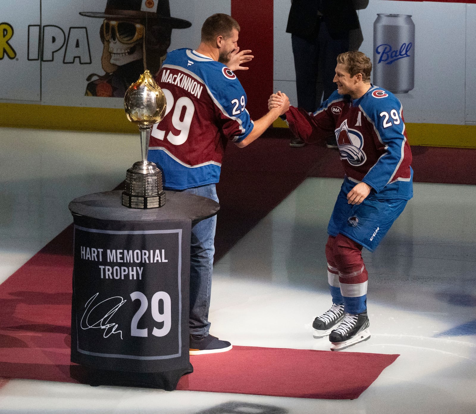 Denver Nuggets center and NBA MVP, left, congratulates Colorado Avalanche center Nathan MacKinnon (29) after McKinnon was awarded his Hart Memorial Trophy for the NHL's MVP before the start of an NHL hockey game against the Columbus Blue Jackets Saturday, Oct. 12, 2024, at Ball Arena in Denver. (Christian Murdock/The Gazette via AP)