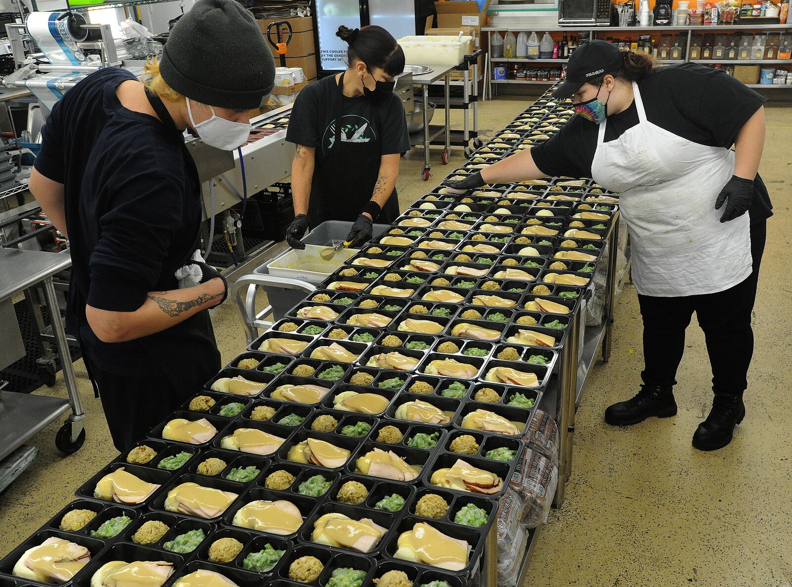 From left, Sean Sibbing,  Angie Abnett and Ashley Purvis help Miami Valley Meals in preparing 15,000 meals for Thanksgiving. The meals include turkey, gravy, stuffing, mash potatoes, green beans and pumpkin roll. MARSHALL GORBY\STAFF