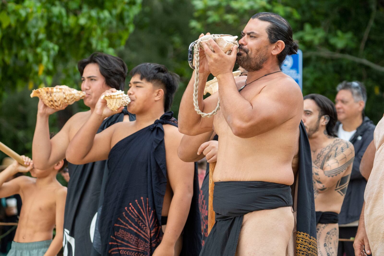 Hawaiian culture practitioners blow conch shells to welcome Hokulea during its 50th birthday commemoration at Kualoa Regional Park, Saturday, March 8, 2025, in Kaneohe, Hawaii. (AP Photo/Mengshin Lin)