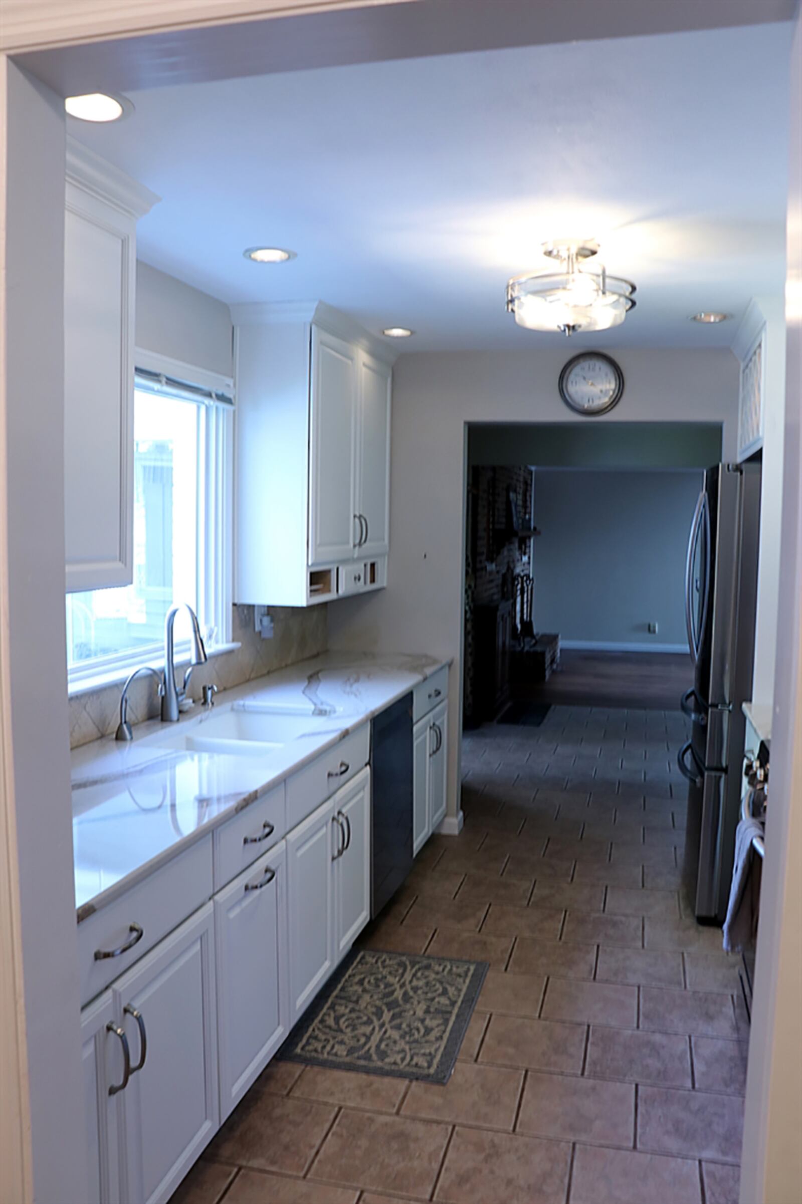 The galley kitchen has been updated with white cabinetry and granite countertops. A window is above the double sink, and stainless-steel appliances include a gas range, microwave, dishwasher and refrigerator. CONTRIBUTED PHOTO BY KATHY TYLER