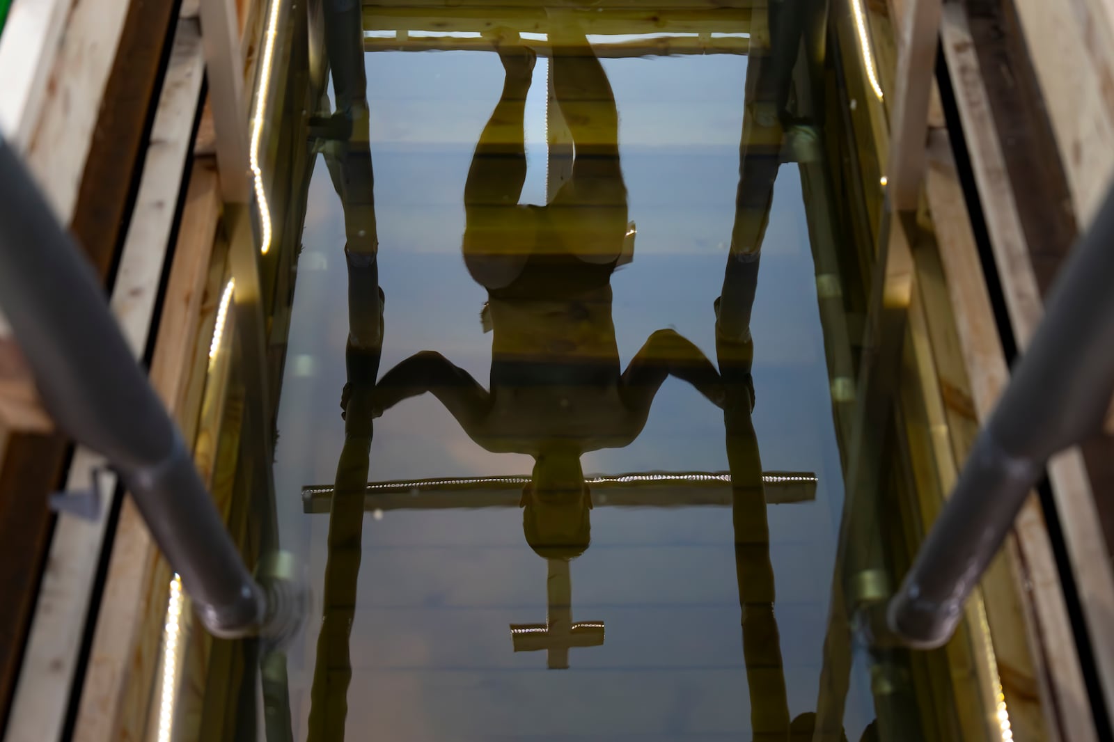 A man steps down to plunge as a cross is reflected in icy water before celebrating the Orthodox Epiphany in the Stroginskaya floodplain in Moscow, Russia, on Sunday, Jan. 19, 2025. (AP Photo/Alexander Zemlianichenko)