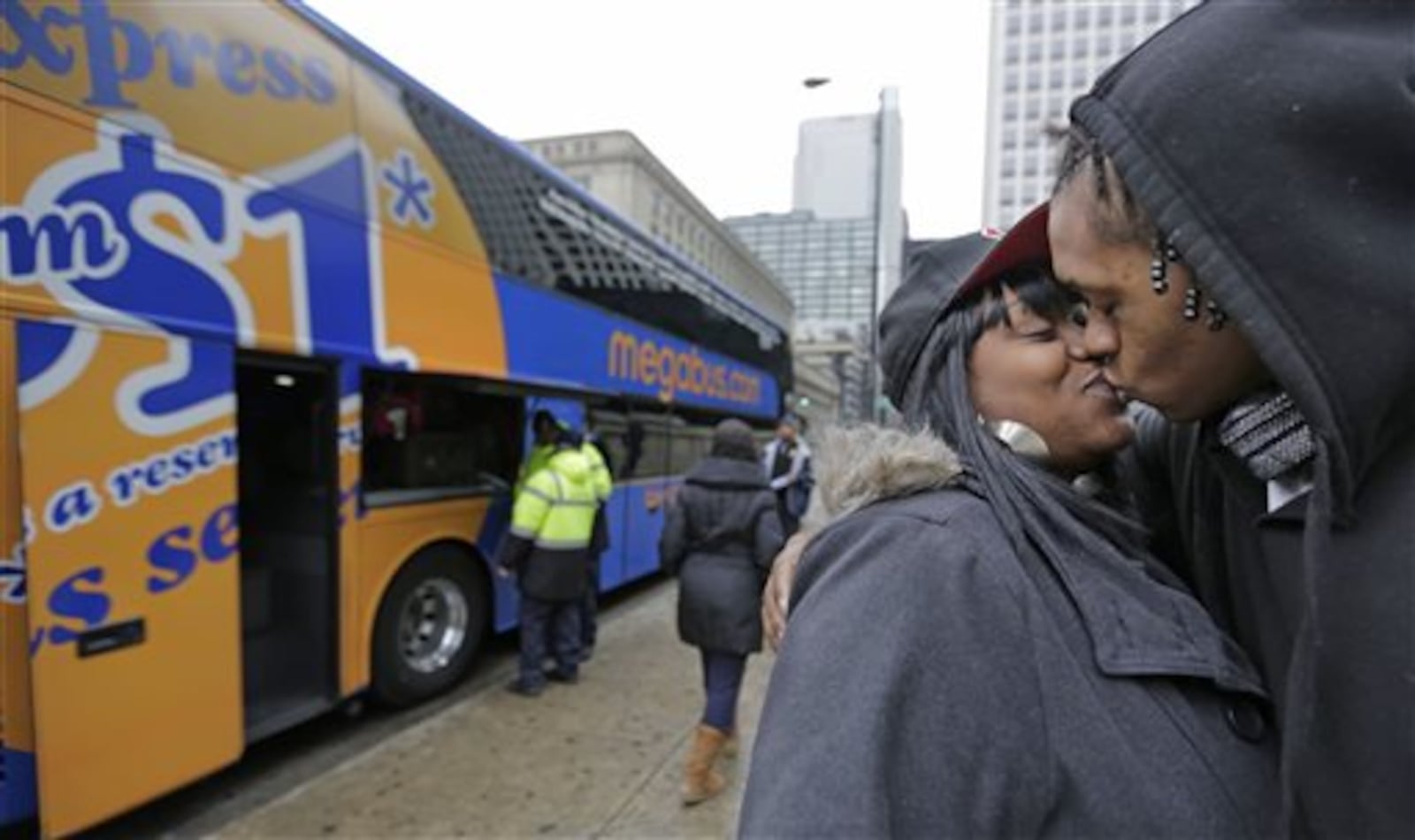 Shay Owens kisses her boyfriend Bryan Jordan before boarding a Megabus for a trip to Atlanta, Tuesday, Nov. 26, 2013, in Chicago. Millions of Americans are hurtling along the nation's jumble of transportation arteries for Thanksgiving, and more of them are discovering that a bus, of all things, is the cheapest, comfiest and coolest way to stay Zen during the nation's largest annual human migration. (AP Photo/M. Spencer Green)