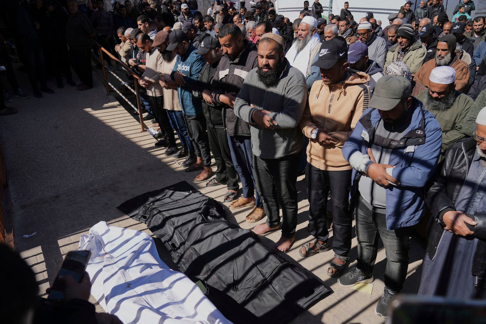 Mourners pray next to the bodies of their Palestinians killed in the Israeli bombardment of the Gaza Strip as they are brought for burial at Nasser Hospital in Khan Younis, Sunday, March 23, 2025. (AP Photo/Abdel Kareem Hana)