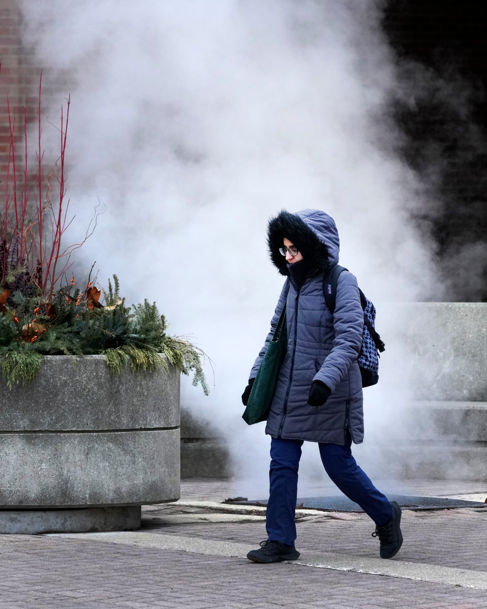 A pedestrian walks past steam released in the air as an Arctic blast brings single-digit temperatures with wind chills below zero on Thursday, Dec. 12, 2024, in Chicago. (AP Photo/Charles Rex Arbogast)