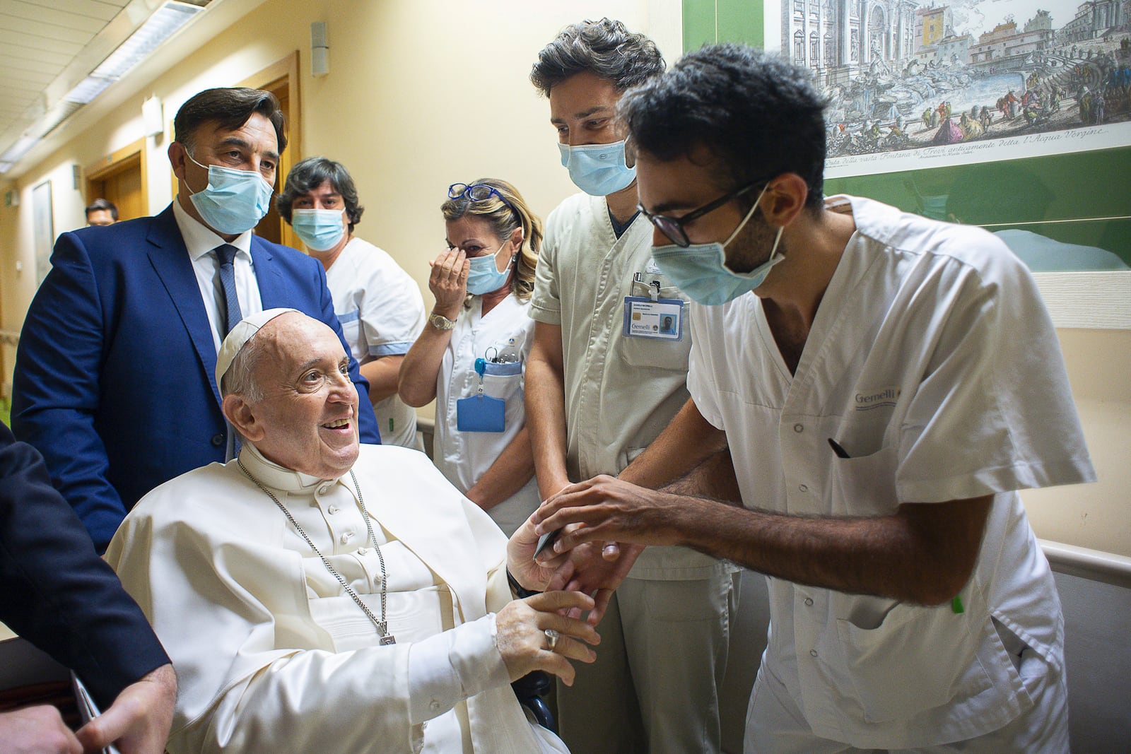 FILE - Pope Francis is greeted by hospital staff as he sits in a wheelchair inside the Agostino Gemelli Polyclinic in Rome, Sunday, July 11, 2021, where he was hospitalized for intestine surgery. (Vatican Media via AP, file)