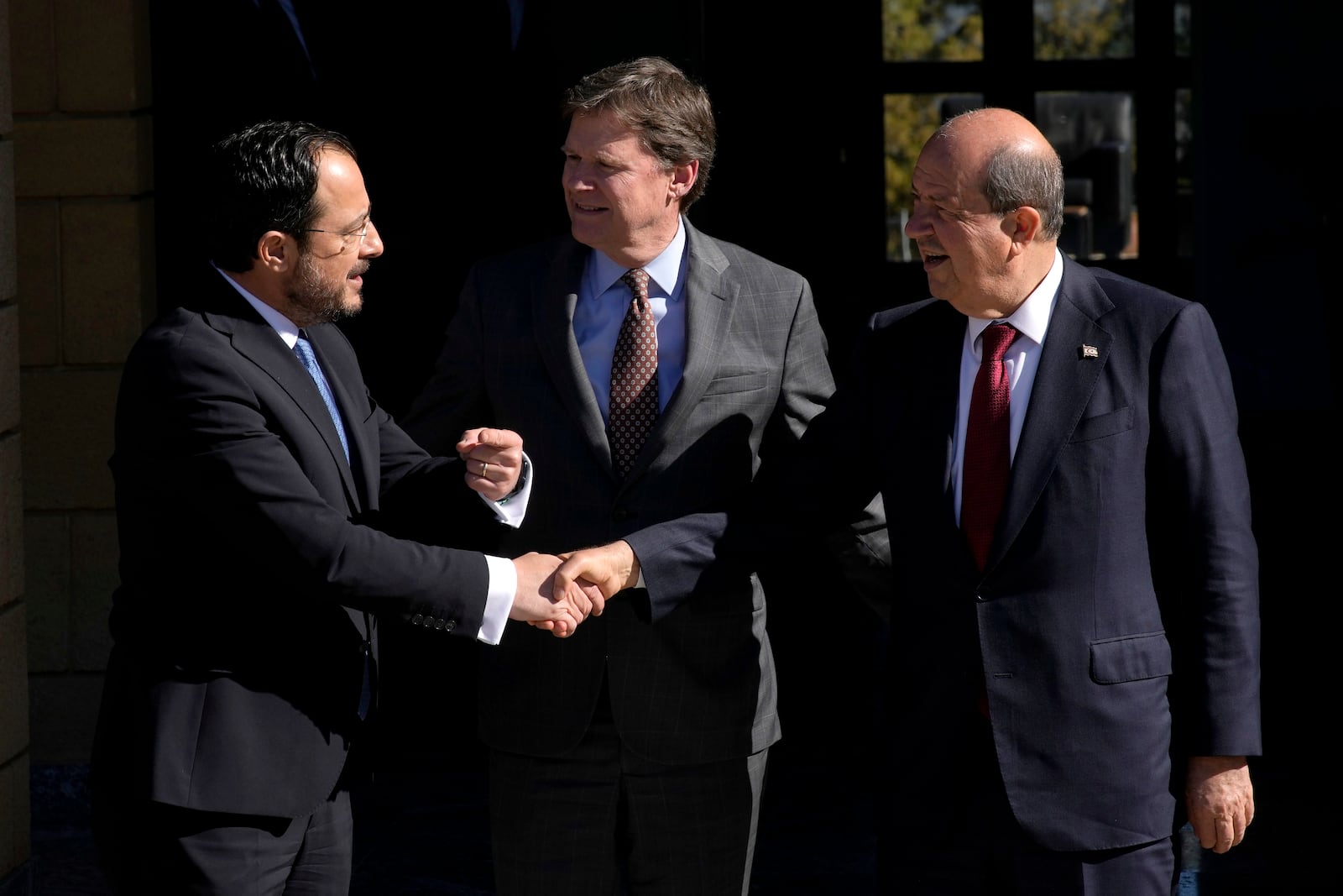 United Nations Chief of Mission in Cyprus Colin Stewart, center, looks at Cypriot President Nikos Christodoulides, left, as he shakes hands with leader of the breakaway Turkish Cypriots Ersin Tatar after their meeting at the U.N. official's residence inside a U.N.-controlled buffer zone cutting across the divided capital Nicosia, Cyprus, Monday, Jan. 20, 2025. (AP Photo/Petros Karadjias)