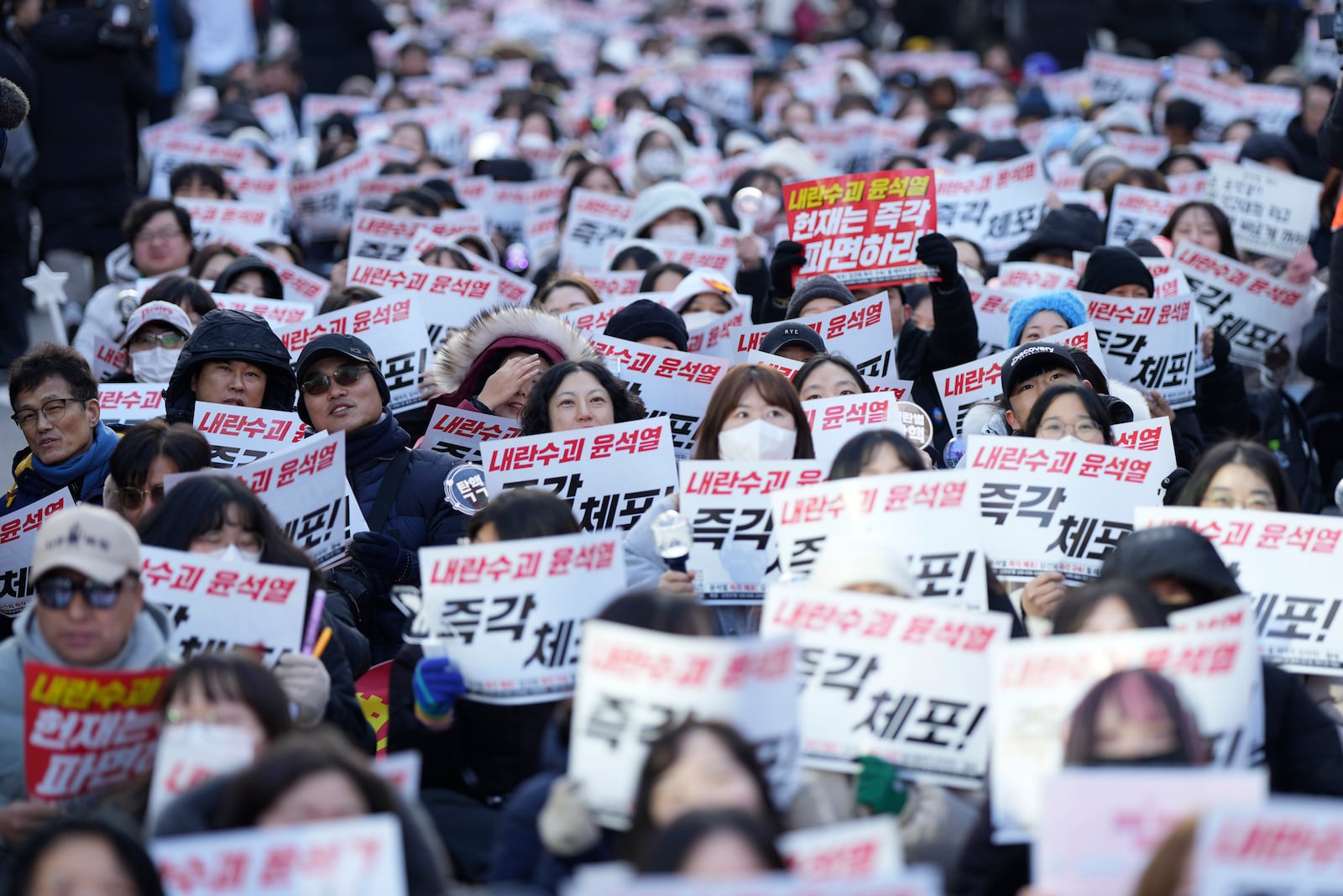 Participants shout slogans during a rally calling on the Constitutional Court to dismiss the President Yoon Suk Yeol in Seoul, South Korea, Sunday, Dec. 15, 2024. The signs read "Immediately arrest." (AP Photo/Lee Jin-man)