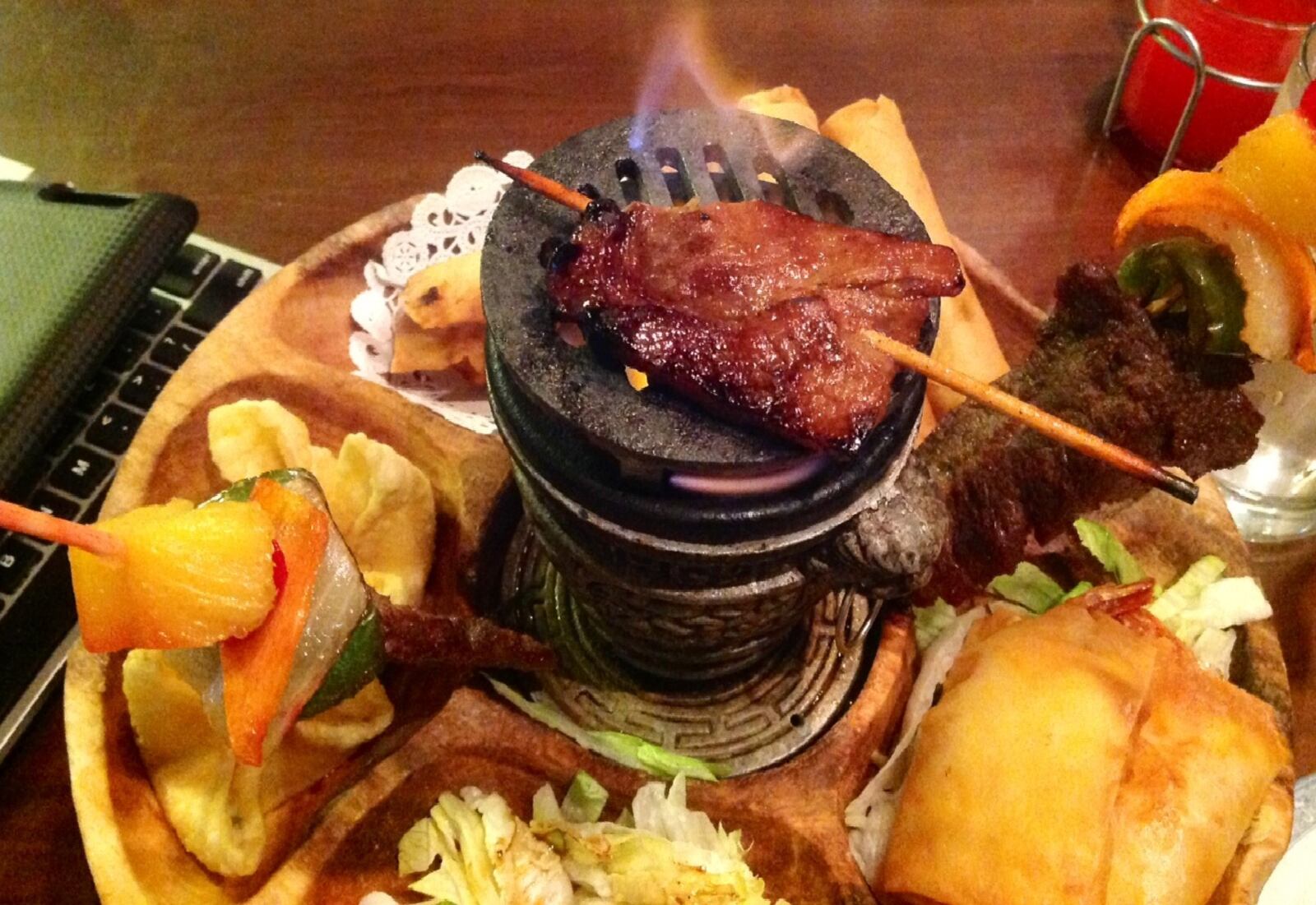 China Cottage owner Tiger Wang said small charcoal grill in the center of the round platter should be used to keep the Marinated Beef Sticks warm. It does the trick with the B.B.Q. Boneless Pork too. (Staff photo by Amelia Robinson)