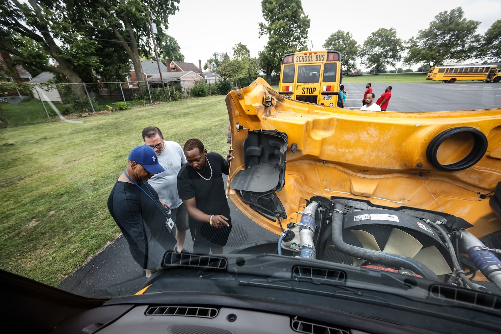 Dayton public schools bus drivers in training from left, Barry Payne, Tim Walden and Darell Henderson go through an engine check-list while learning to drive a school bus at the Welcome Stadium parking lot Tuesday August 9, 2022. JIM NOELKER/STAFF