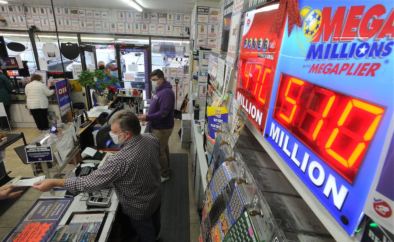 Michael Sliger, front, and Ben Lovins, help customers with their purchase of Mega Millions Tickets at Bee-Gee's Mini Market in Kettering, Thursday, Jan. 7, 2021. MARSHALL GORBY\STAFF