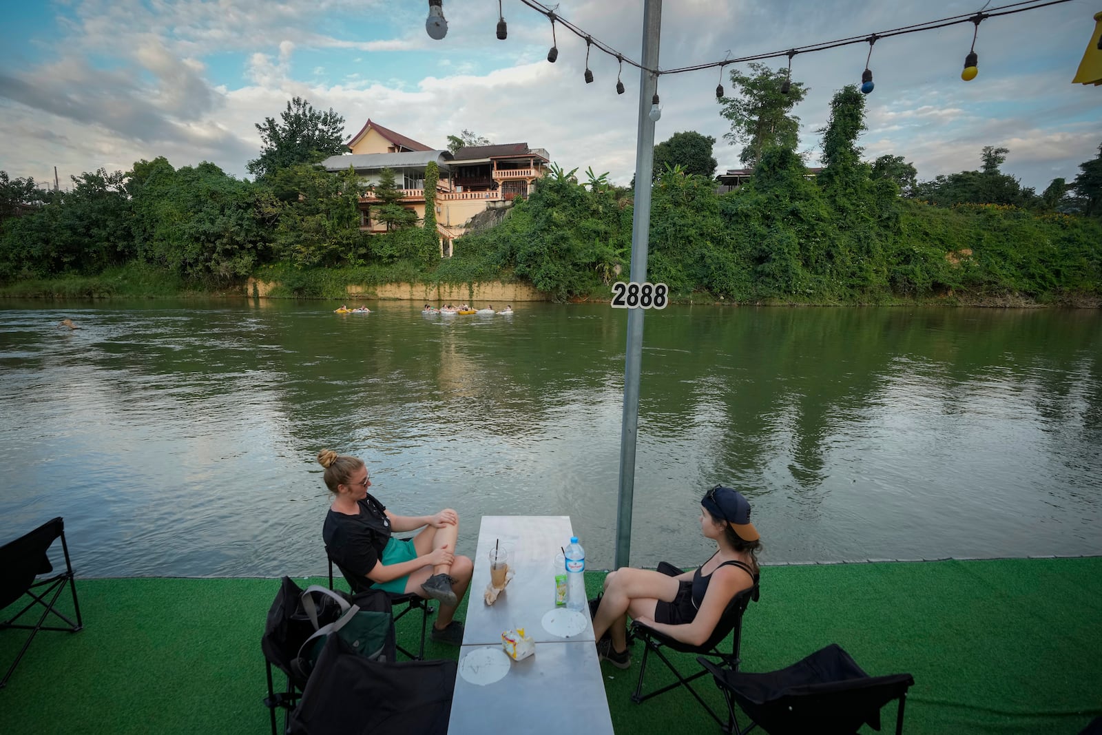 Foreign tourists drink beer at a bar near a river in Vang Vieng, Laos, Tuesday, Nov. 19, 2024. (AP Photo/Anupam Nath)