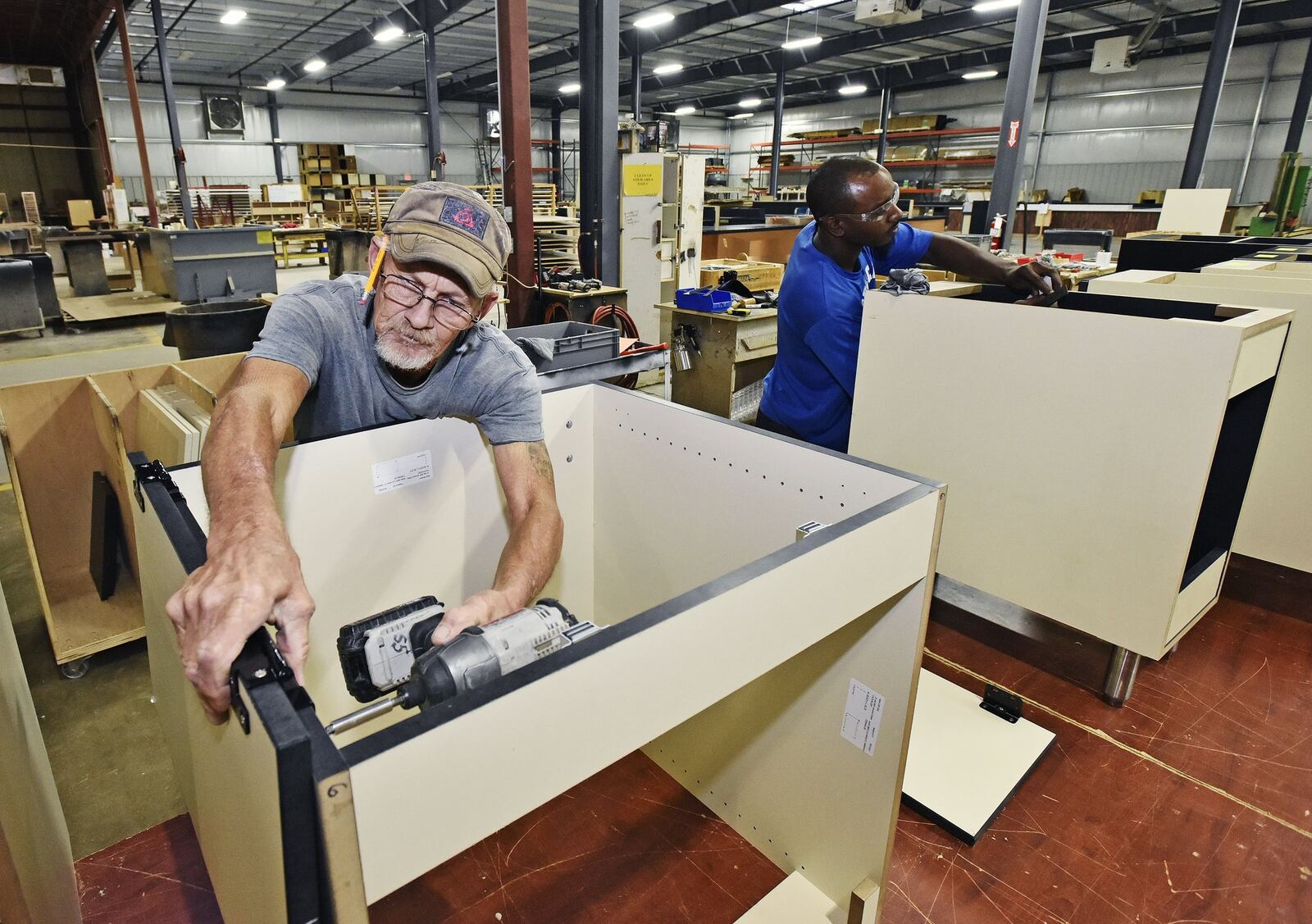 Jesse Combs, left, and Devinn Parms build cabinets at Custom Millcraft Corporation Tuesday, Oct. 10 in West Chester Twp. The fixture manufacturer specializes in high-end fixture work and complete millwork packages for retail, restaurant, banking and healthcare industries. The company, which is expanding its workforce, says lack of skilled labor has been detrimental to growing its business. NICK GRAHAM/STAFF