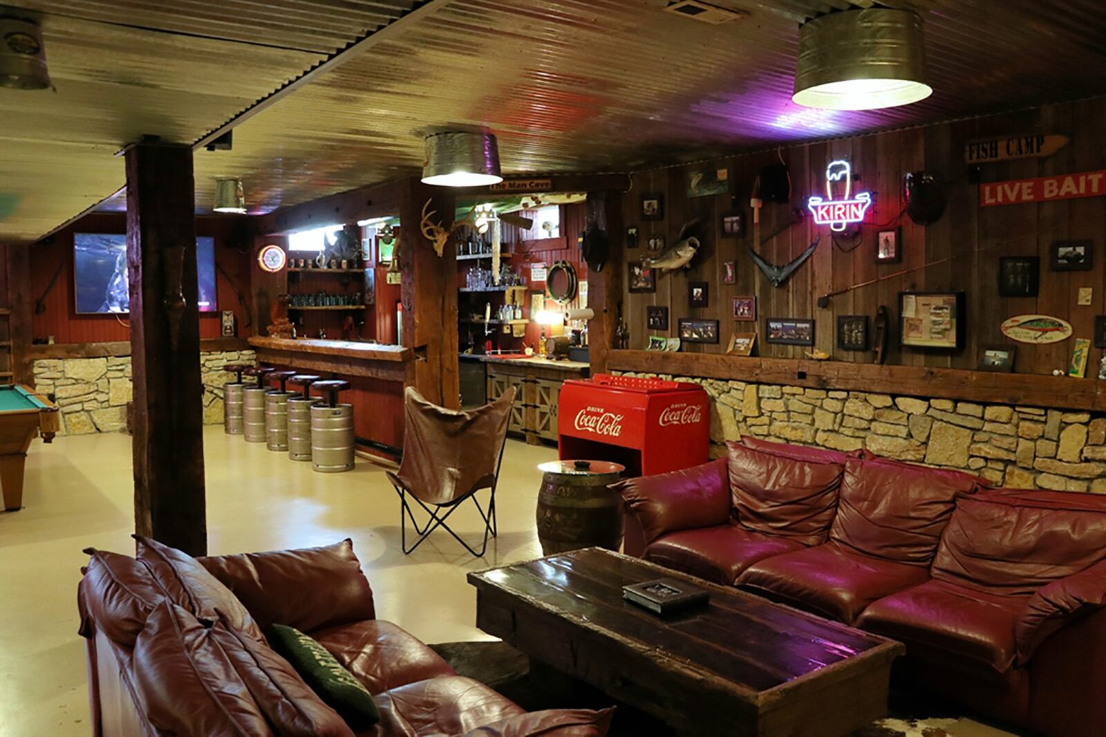 A finished recreation room in the walk-out lower level has repurposed barn siding, stone wainscoting and a tin-panel ceiling treatment. A 6-seat bar is made from hand-carved oak barn beam. CONTRIBUTED PHOTO BY KATHY TYLER