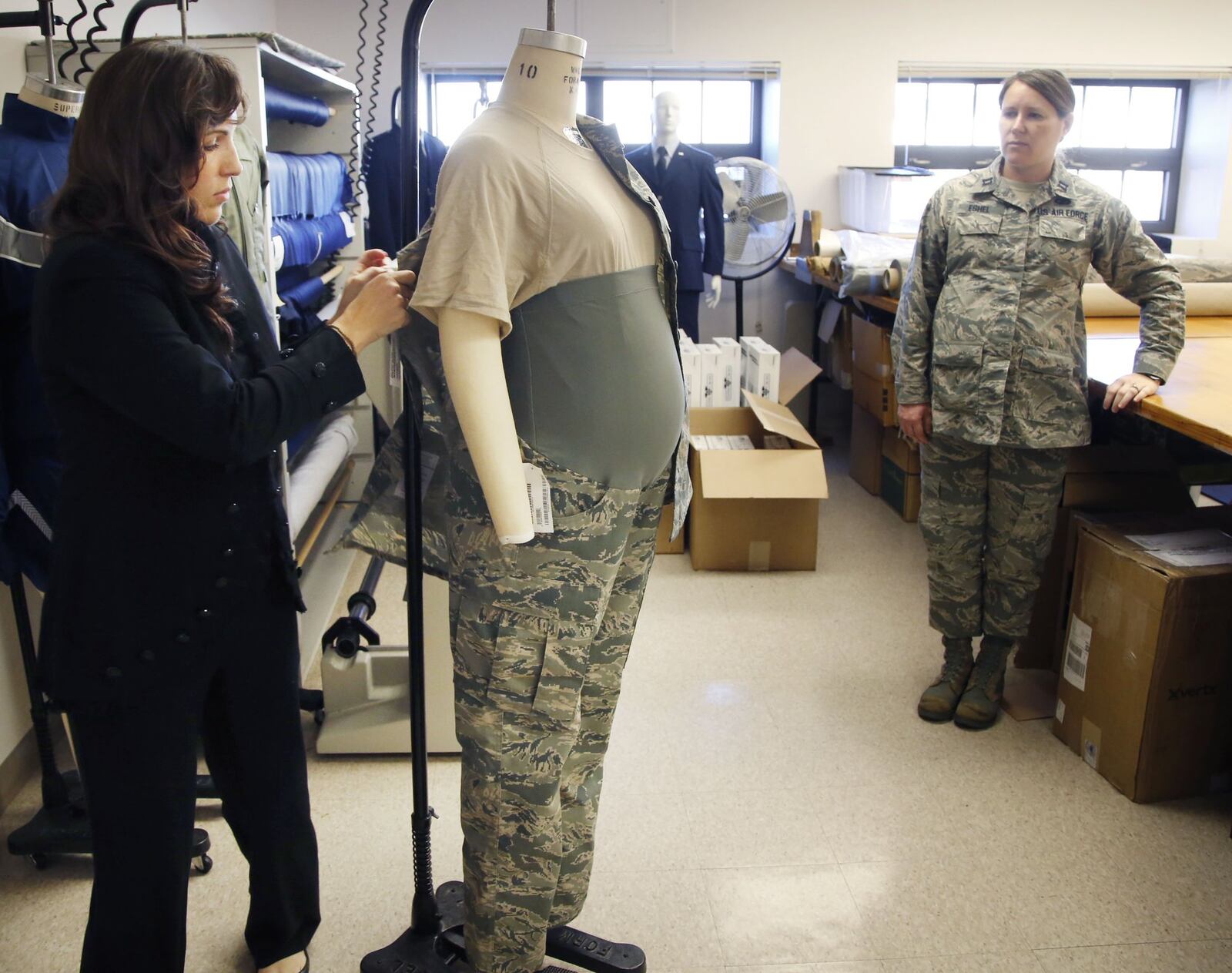 Air Force Uniform Office clothing designer Stacey Butler, left, adjusts an improved maternity uniform prototype on a mannequin that is also being tested by a pregnant Capt. Mollie Eshel, right, in 2016 at Wright-Patterson Air Force Base. TY GREENLEES / STAFF