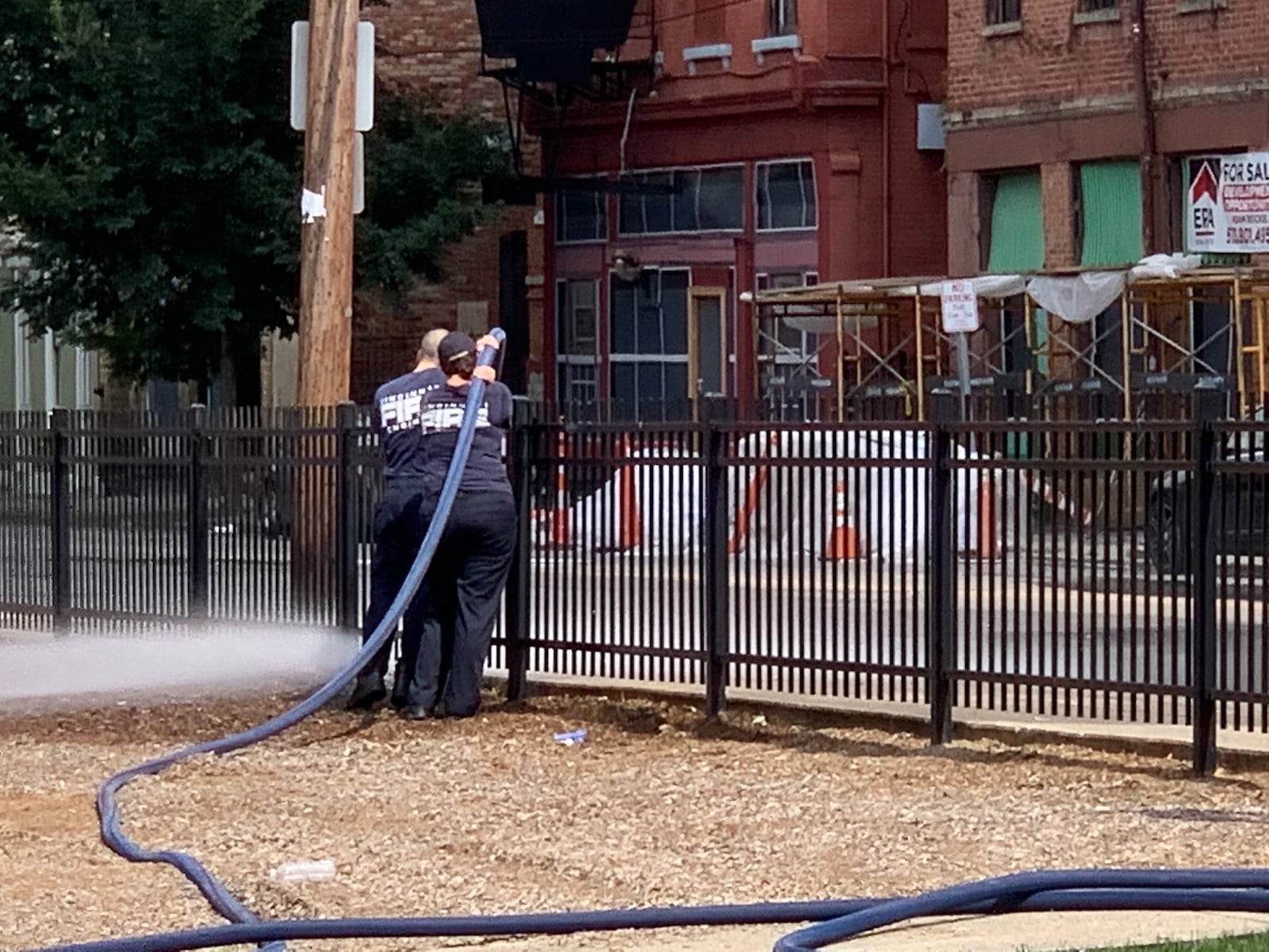 Firefighters spray blood off the pavement on McMicken Avenue in Cincinnati, where 10 people were shot and two died overnight Sunday police said. three other shootings occurred in other locations in the city, and a total of 18 people were shot, including four fatalities. The shootings were unrelated, officers said./Ed Richter