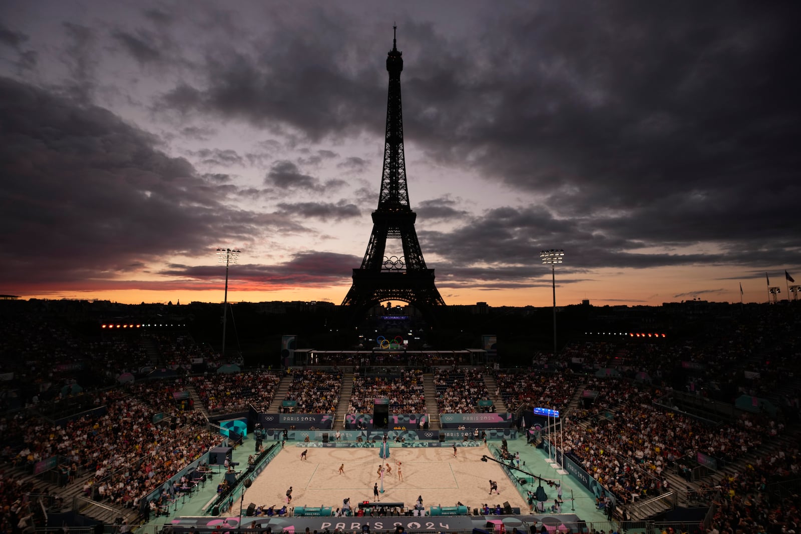 FILE - The Eiffel Tower looms in the background during play in the women's beach volleyball bronze medal match between Australia, left, and Switzerland, right, at the 2024 Summer Olympics, Aug. 9, 2024, in Paris, France. (AP Photo/Louise Delmotte, File)