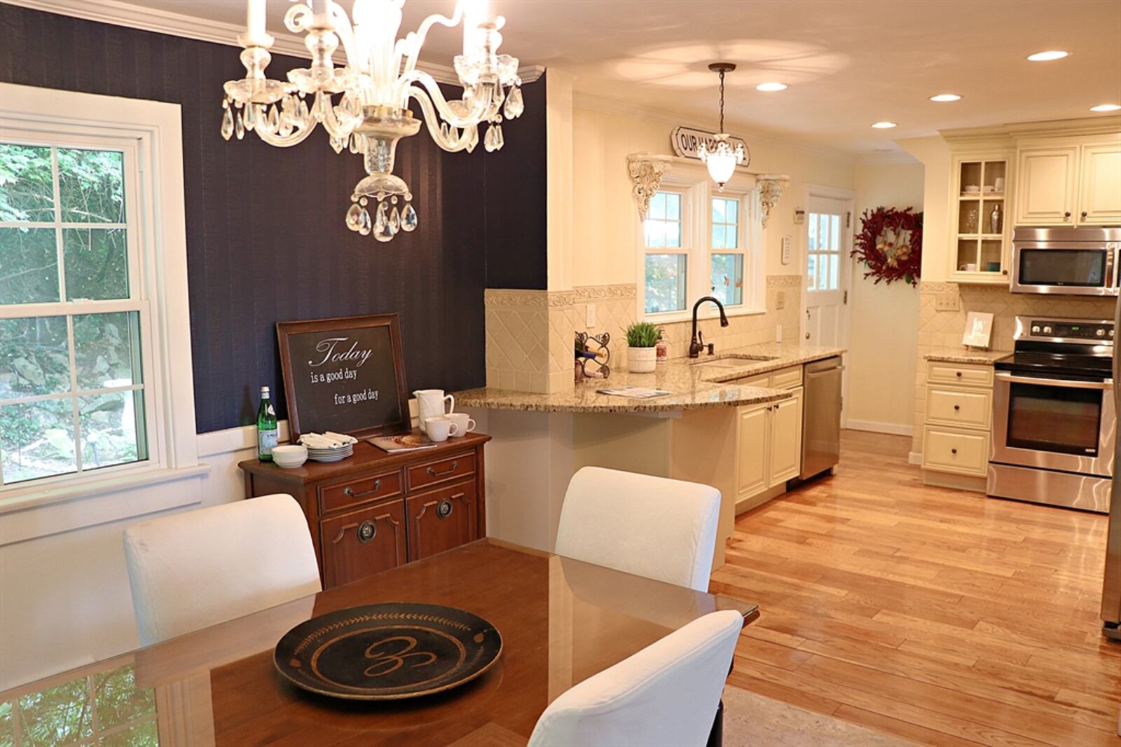 Open off the dining room — yet divided by a peninsula counter — is the updated kitchen. Antique white cabinetry fills three walls and wraps around stainless-steel appliances. 