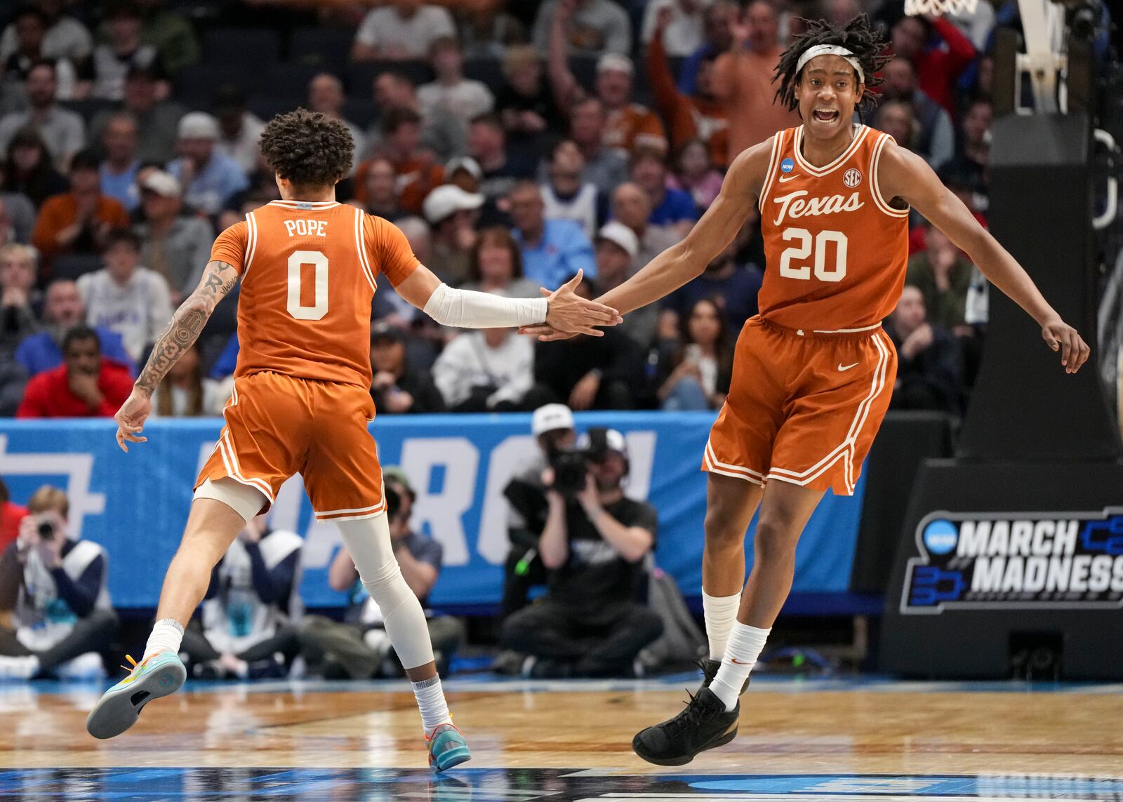 Texas' Jordan Pope (0) celebrates with teammate Tre Johnson (20) during the first half of a First Four college basketball game against Xavier in the NCAA Tournament, Wednesday, March 19, 2025, in Dayton, Ohio. (AP Photo/Jeff Dean)