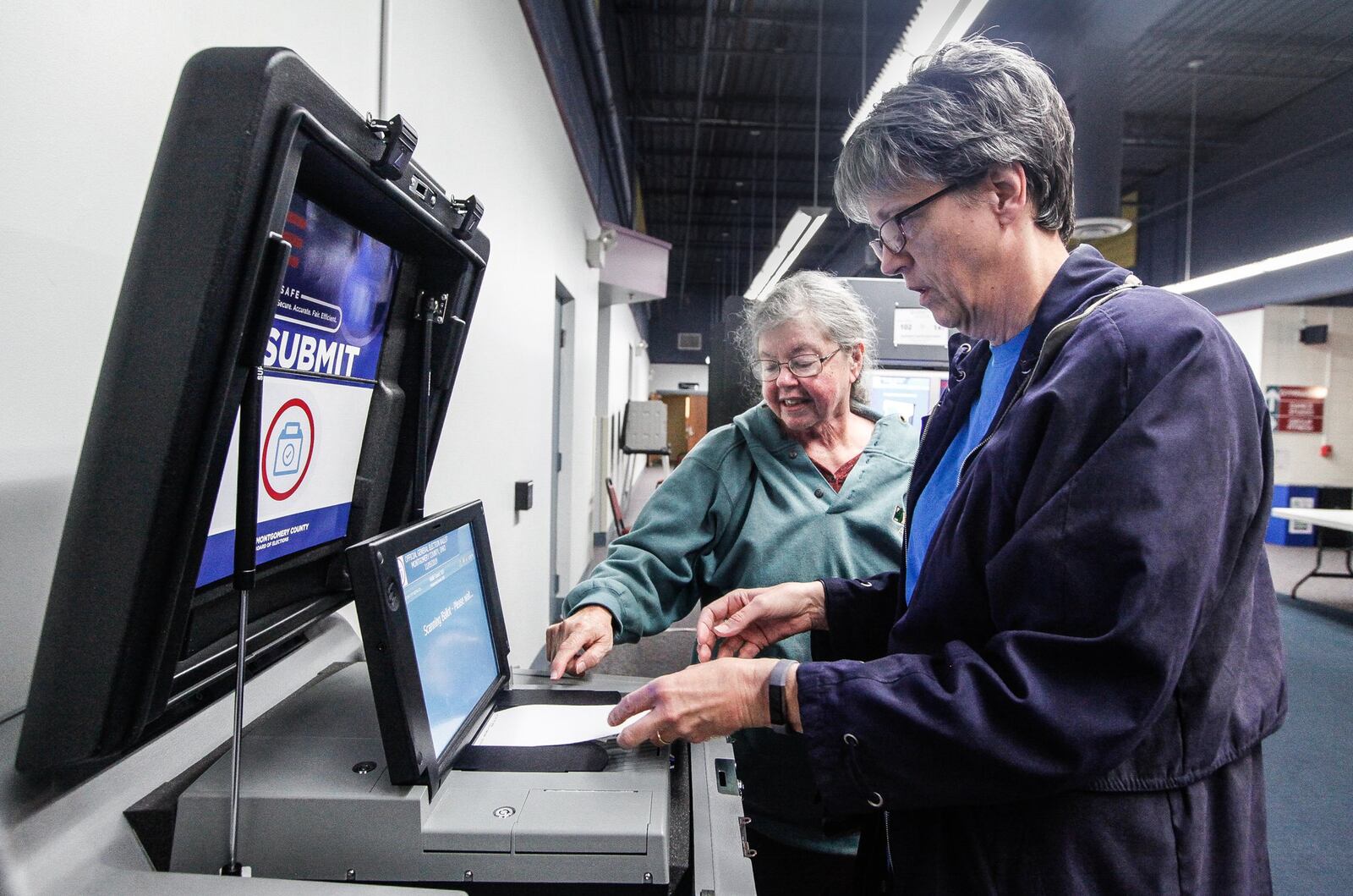 Washington Twp. voter Linda Hunter feeds her ballot into a new machine Tuesday with the help of poll worker Terrie Gutwein at the Washington Twp. Recreation Center. CHRIS STEWART / STAFF