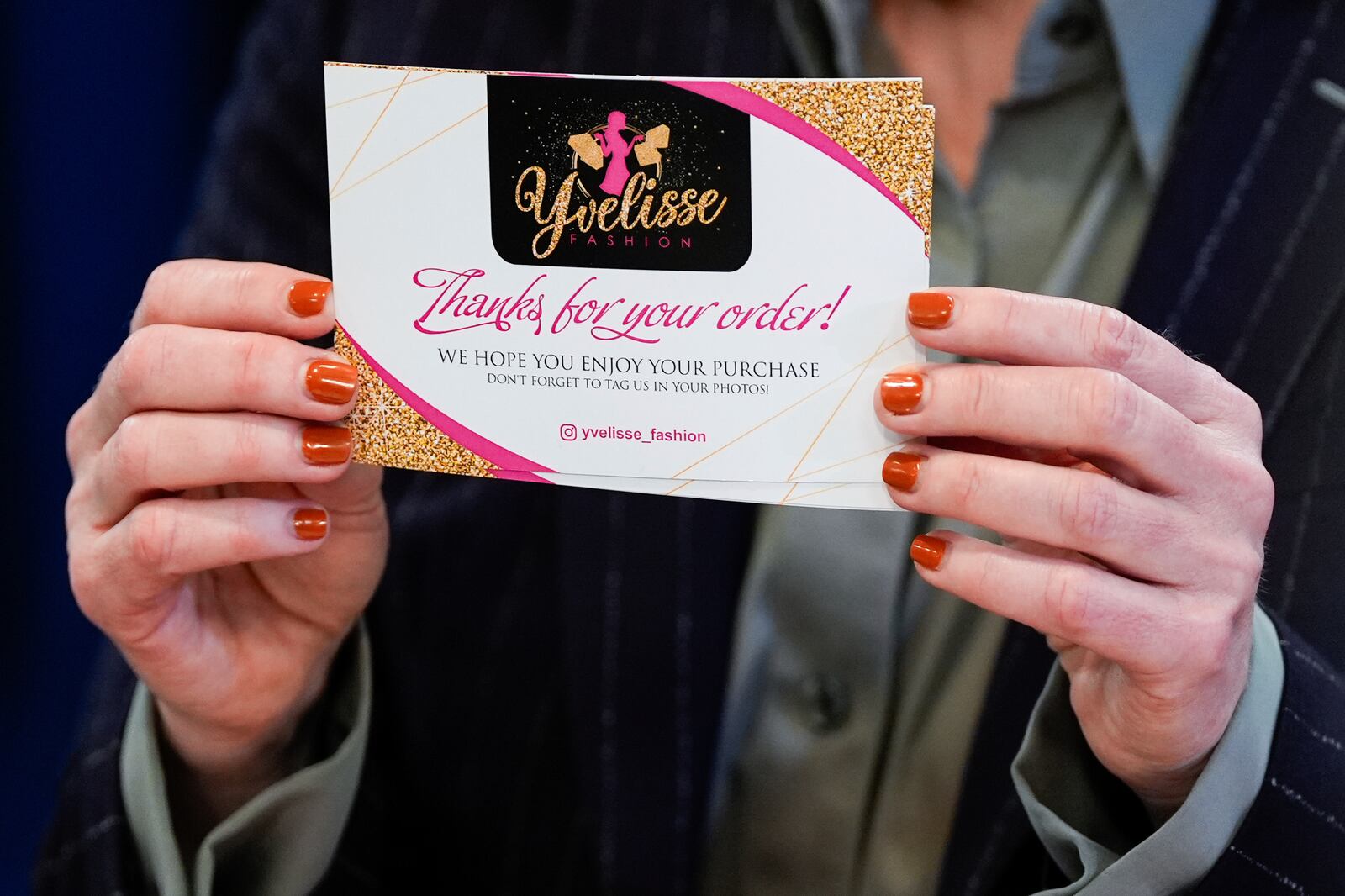 Queens District Attorney Melinda Katz shows a business card during a news conference on an international stolen merchandise ring, Tuesday, Nov. 26, 2024, in the Queens borough of New York. (AP Photo/Julia Demaree Nikhinson)