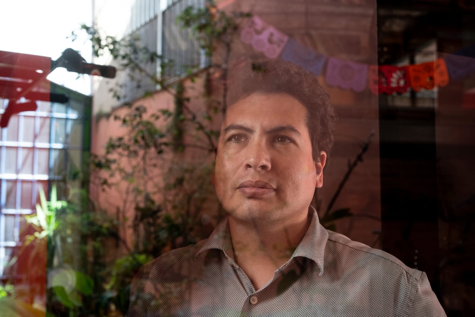 Photographed through a window, lawyer Jonatan Baldiviezo poses for the portrait during an interview at his home in Buenos Aires, Argentina, Monday, Feb. 17, 2025. (AP Photo/Rodrigo Abd)