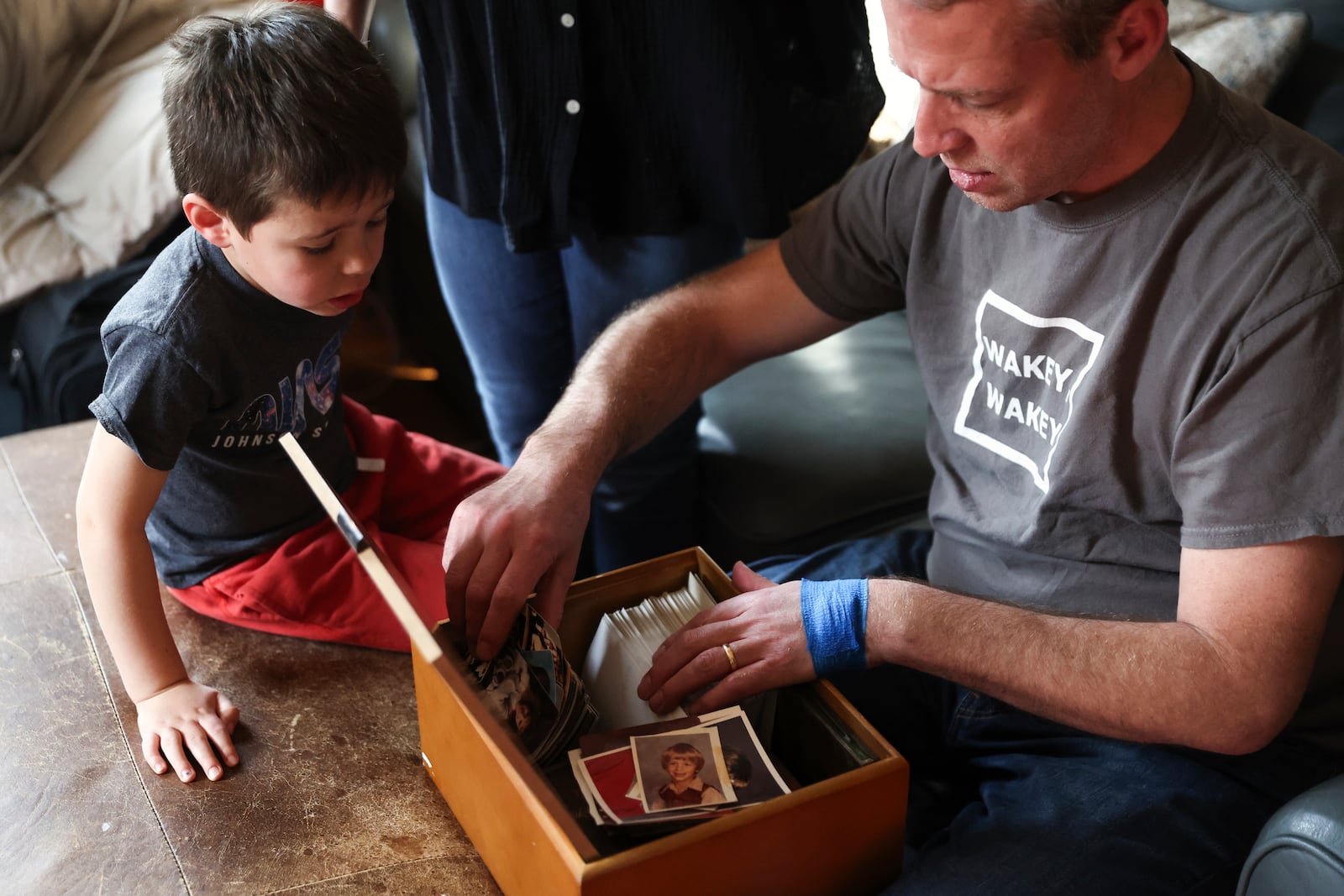 Jake Heinrichs looks through old family photos with his son, Sam, on Wednesday, March 12, 2025, in New York. (AP Photo/Heather Khalifa)