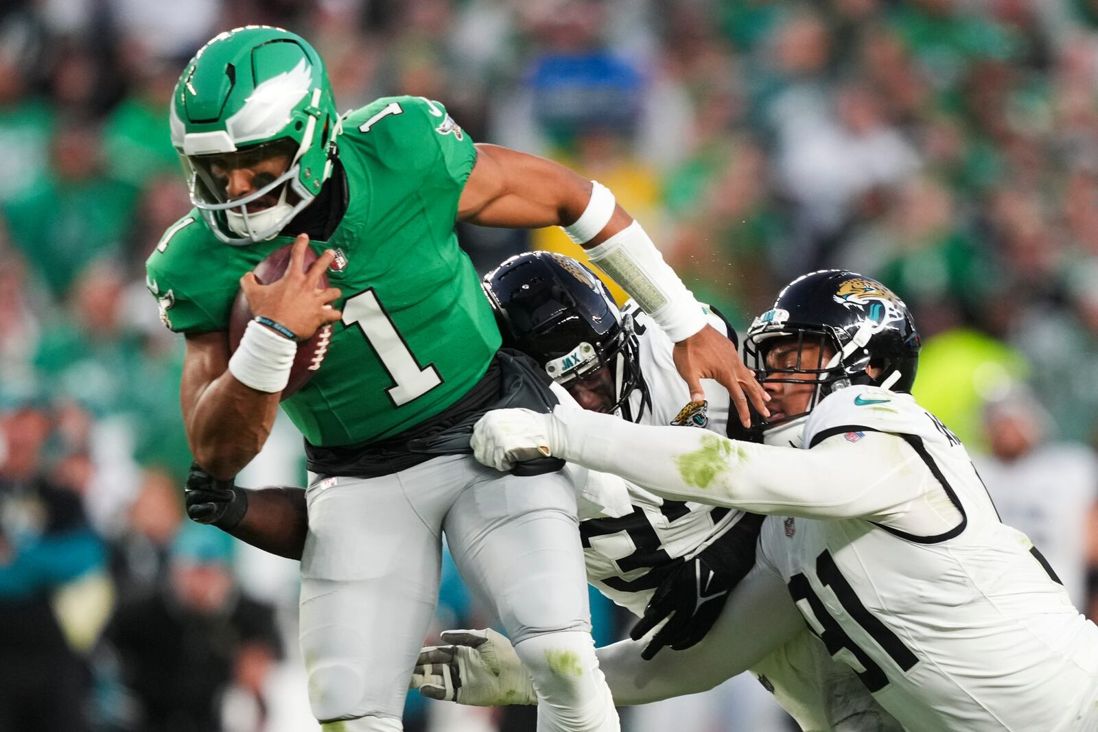 Philadelphia Eagles quarterback Jalen Hurts (1) scrambles under pressure from Jacksonville Jaguars linebacker Devin Lloyd, center, and Jaguars defensive end Arik Armstead during the first half of an NFL football game Sunday, Nov. 3, 2024, in Philadelphia. (AP Photo/Matt Slocum)