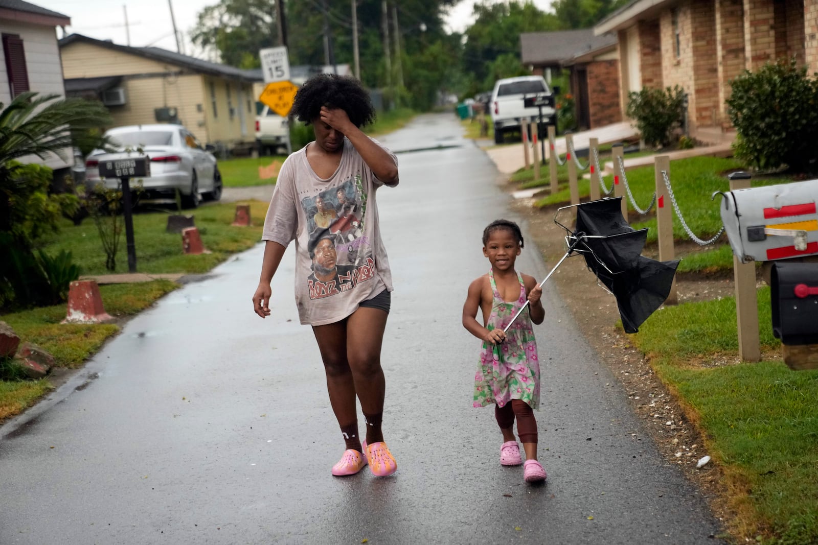 Residents walk down the street in the historic Elkinsville section of in St. Rose, La., Friday, Aug. 16, 2024. (AP Photo/Gerald Herbert)