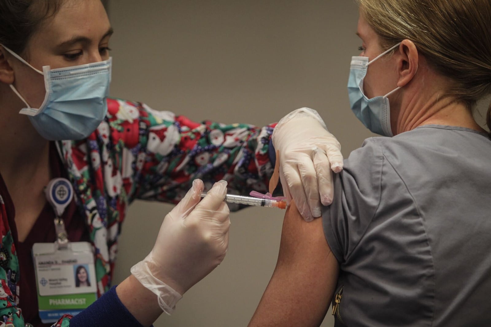 Premier Health pharmacist, Amanda Deskins gives a COVID shot to Miami Valley Hospital emergency room physician Dr. Cathy Marco. who was the first frontline worker at the hospital to be vaccinated Tuesday, Dec. 22, 2020. JIM NOELKER/STAFF