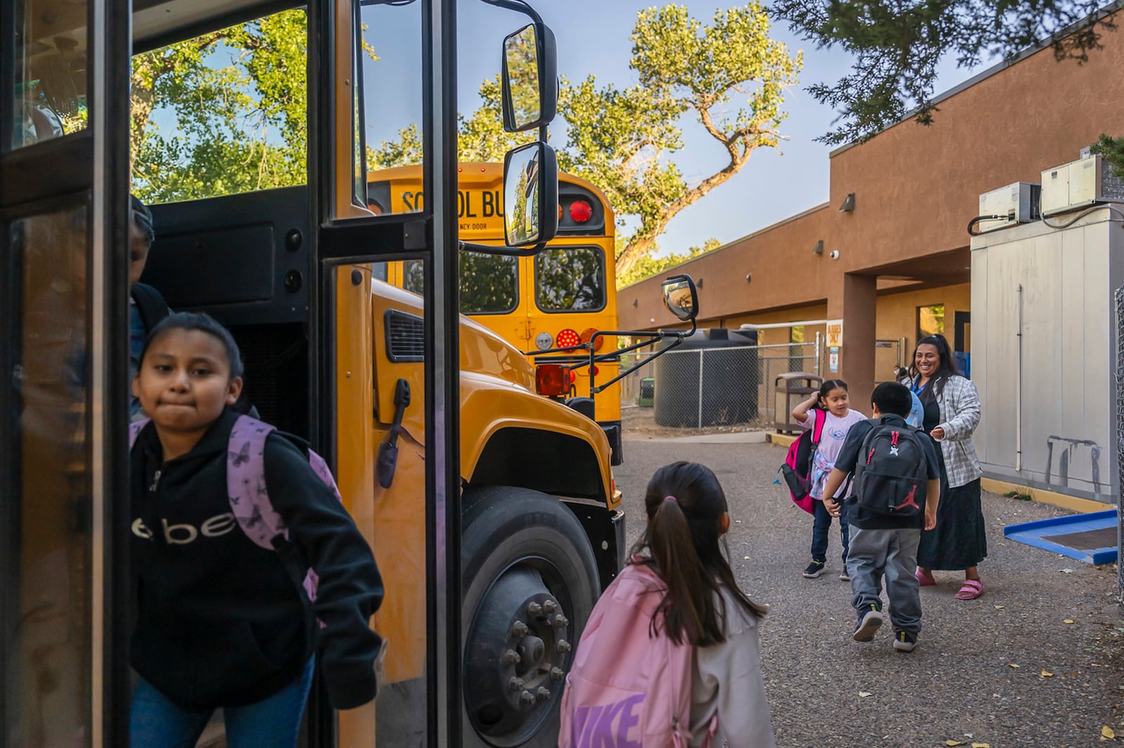 Social worker Mary Schmauss, rear right, greets students as they arrive for school, Tuesday, Oct. 1, 2024, at Algodones Elementary School in Algodones, N.M. (AP Photo/Roberto E. Rosales)