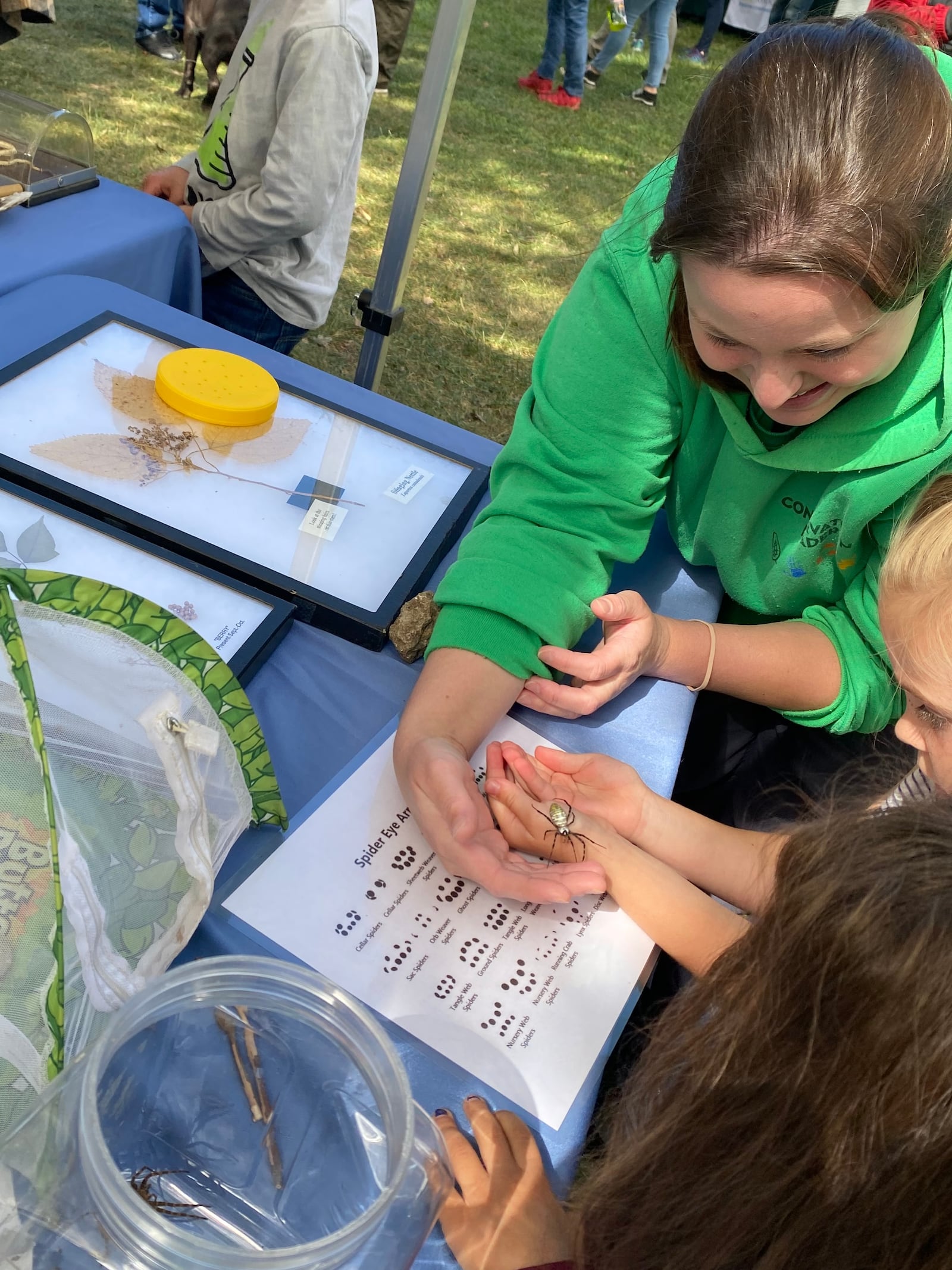 A Five Rivers MetroParks worker shows Mikaela McWest and Diana Pasillas spiders during the Wagner Subaru Outdoor Experience at Eastwood MetroPark Saturday. Eileen McClory/ staff