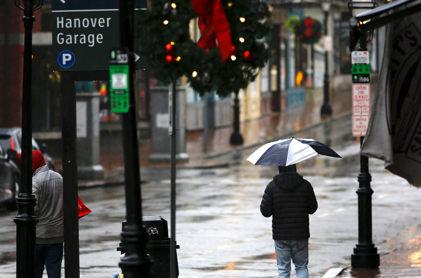 People walk through the rain as a storm system and possible "bomb cyclone" hit the U.S. East Coast, Wednesday, Dec. 11, 2024 in Portsmouth, N.H. (AP Photo/Caleb Jones)