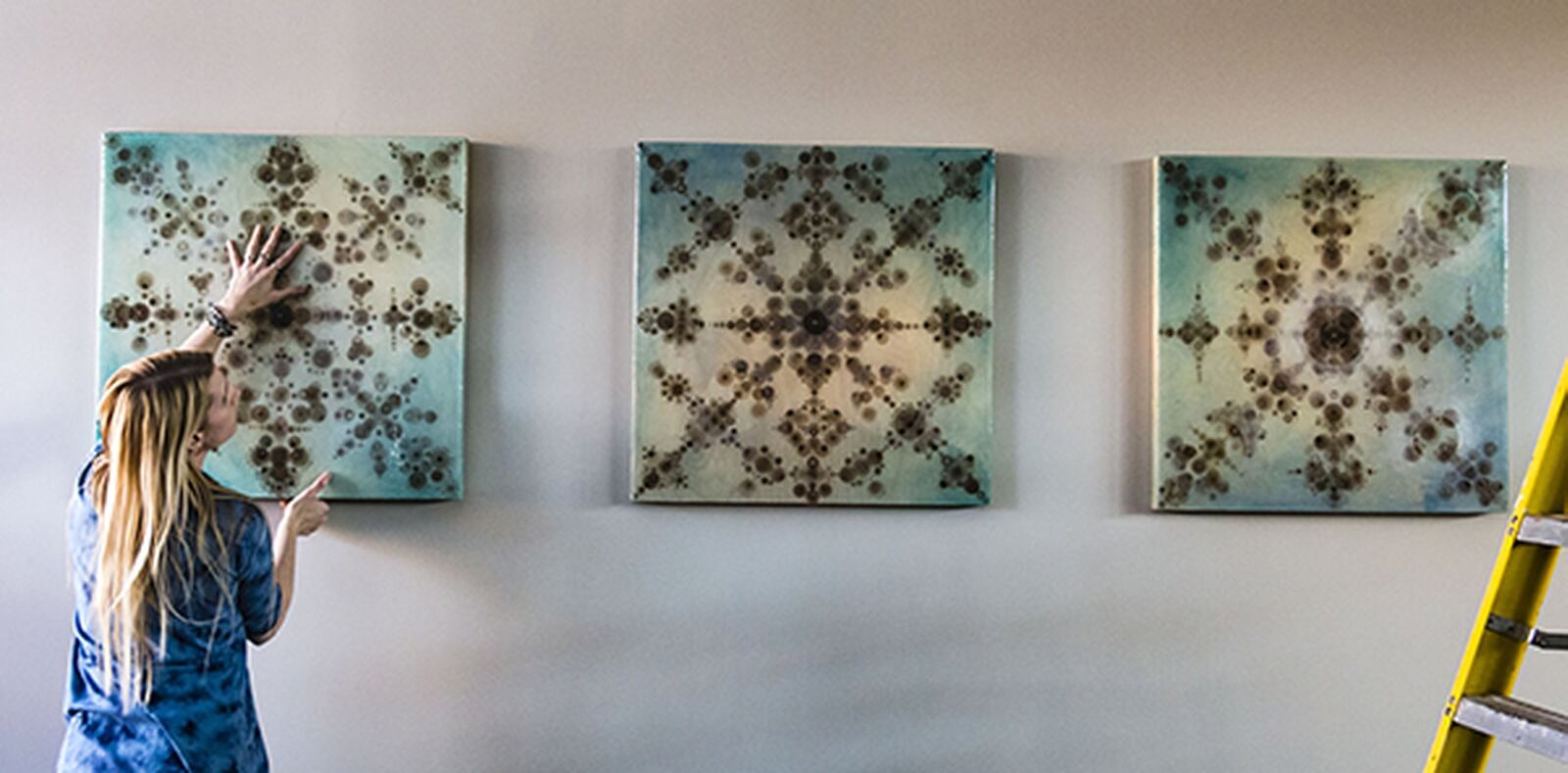 This triptych by artist Amy Kollar Anderson of Dayton is shown installing her triptych in the new Dayton Metro Library Miamisburg branch. SUBMITTED PHOTO BY ANDY SNOW