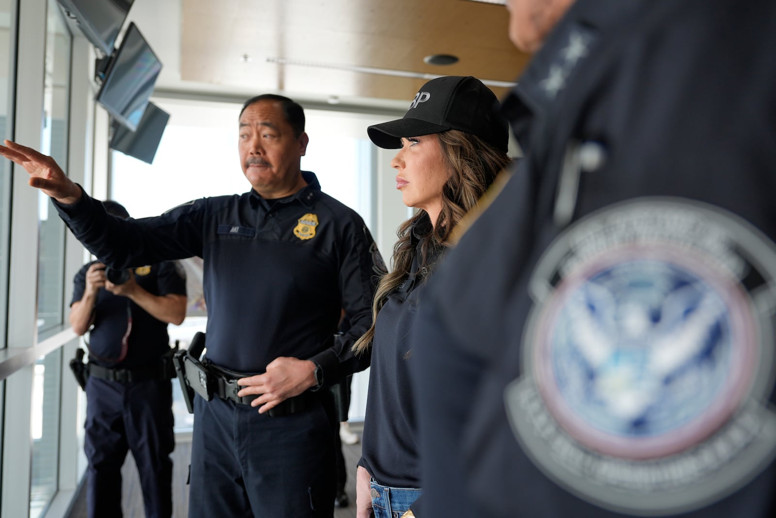 Homeland Security Secretary Kristi Noem, center, listens as Sidney Aki, director of field operations for the Customs and Border Protection (CBP) San Diego field office, left, speaks during a tour of the San Ysidro Port of Entry, Sunday, March 16, 2025, in San Diego. (AP Photo/Alex Brandon)