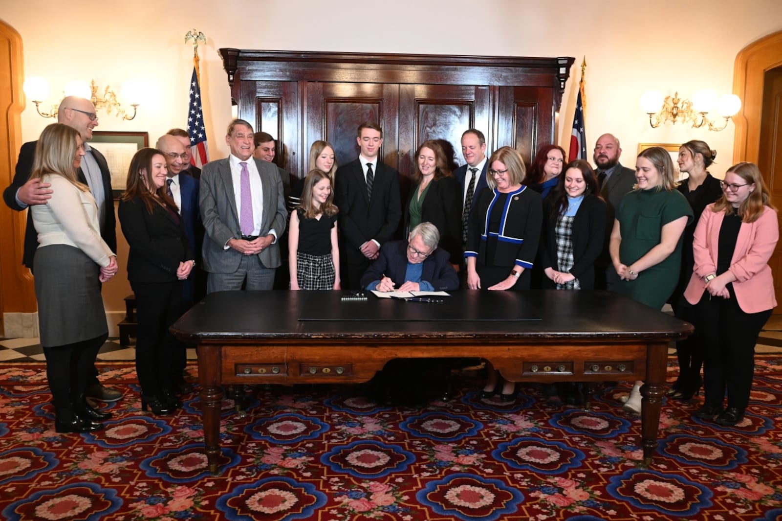 Lawmakers and advocates crowd around Ohio Gov. Mike DeWine on Wednesday, Jan. 8, 2025, as the Republican signs a bill establishing social "grooming" as a criminal offense in Ohio.