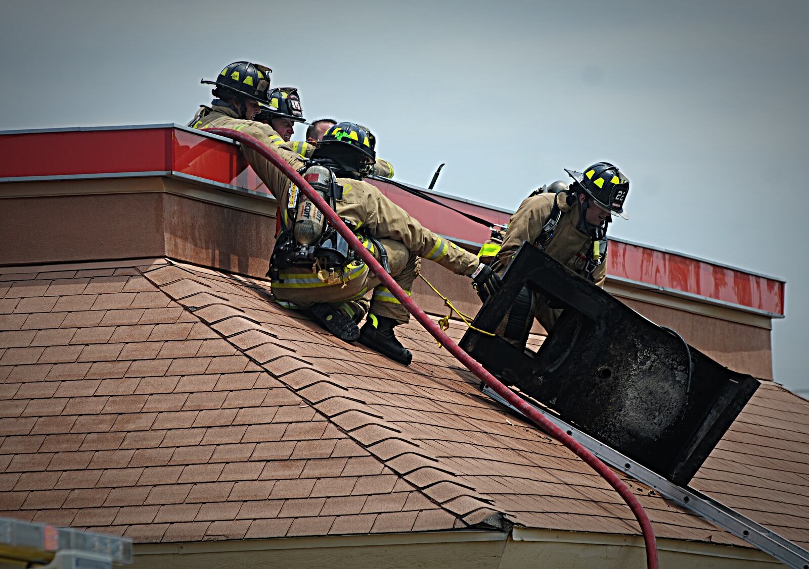 Vandalia firefighters remove a piece of mechanical equipment from the roof of the Burger King, on East National Road, where a fire closed the restaurant until further notice, the fire chief said. (Marshall Gorby/Staff)